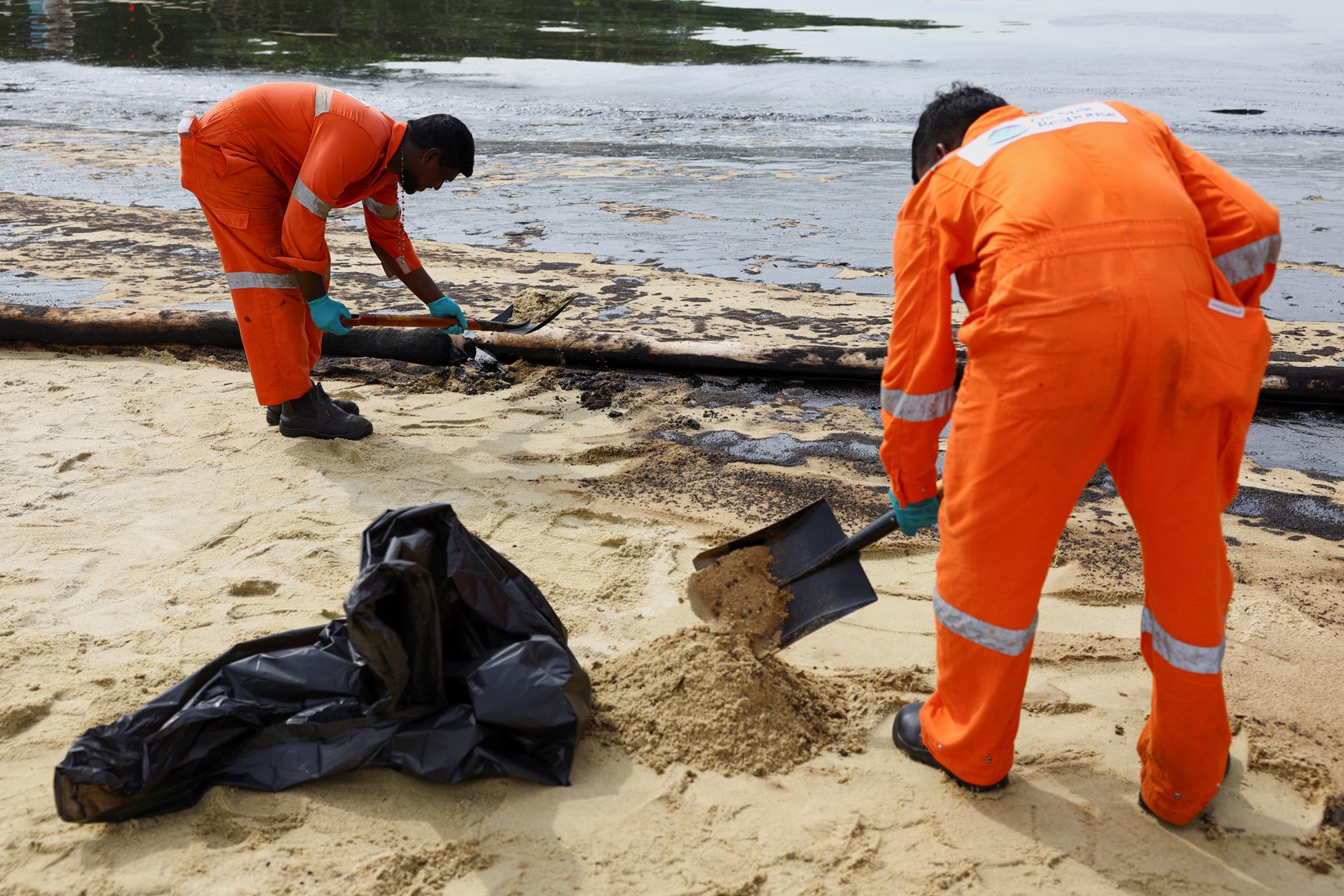 Workers clean up the oil slick at Tanjong Beach in Sentosa, Singapore June 16, 2024. Photo: Reuters