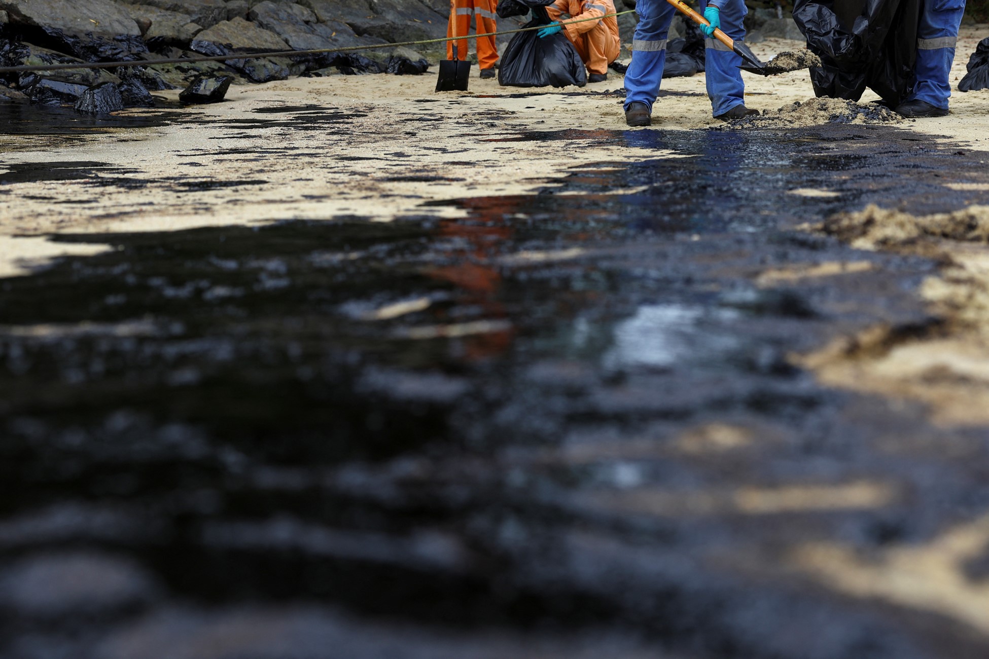 Workers clean up the oil slick at Tanjong Beach in Sentosa, Singapore June 16, 2024. Photo: Reuters