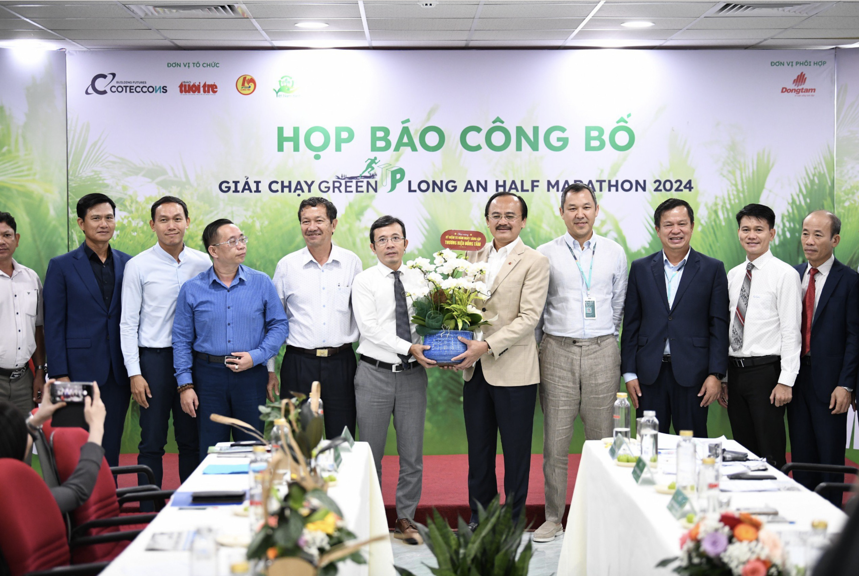 Vo Quoc Thang (right, 5th), chairman and CEO of Dong Tam Group, receives flowers from Tran Xuan Toan, deputy editor-in-chief of Tuoi Tre. Photo: Quang Dinh / Tuoi Tre