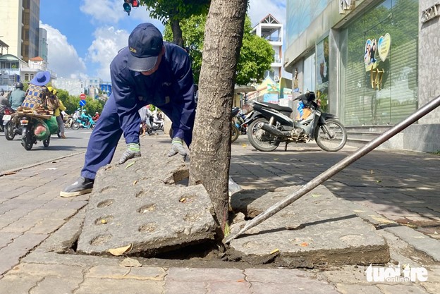 Workers found it hard to remove the concrete layer which is three to four centimeters thick. Photo: Tien Quoc / Tuoi Tre