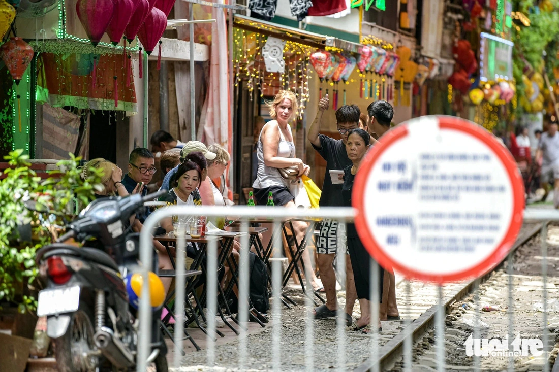 Foreign tourists wait for trains at a coffee shop on the trackside café street in Hanoi. Photo: Nam Tran / Tuoi Tre