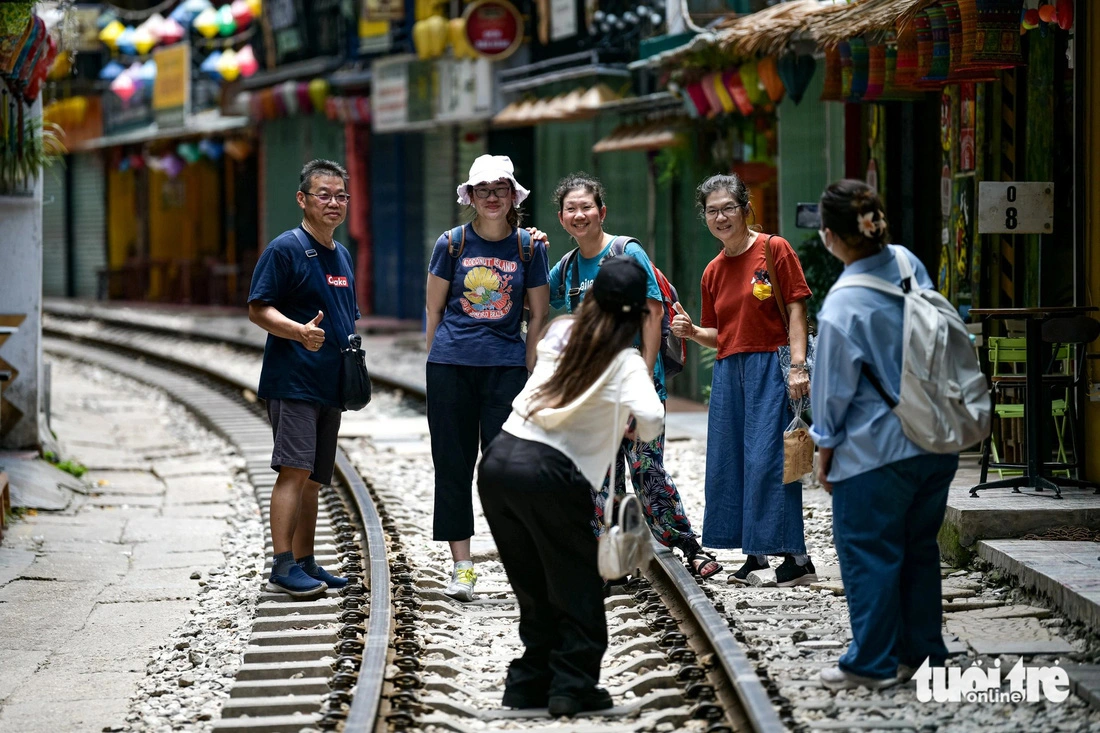 Foreign tourists pose for photos on the tracks down the railway-side café street in Hang Bong Ward, Hoan Kiem District, Hanoi. Photo: Nam Tran / Tuoi Tre