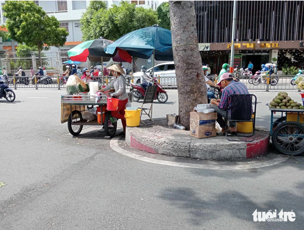 Street vendors take advantage of the concrete over the roots of a tree on Ba Thang Hai Street in District 11, Ho Chi Minh City to sell products. Photo: Dinh Duong / Tuoi Tre