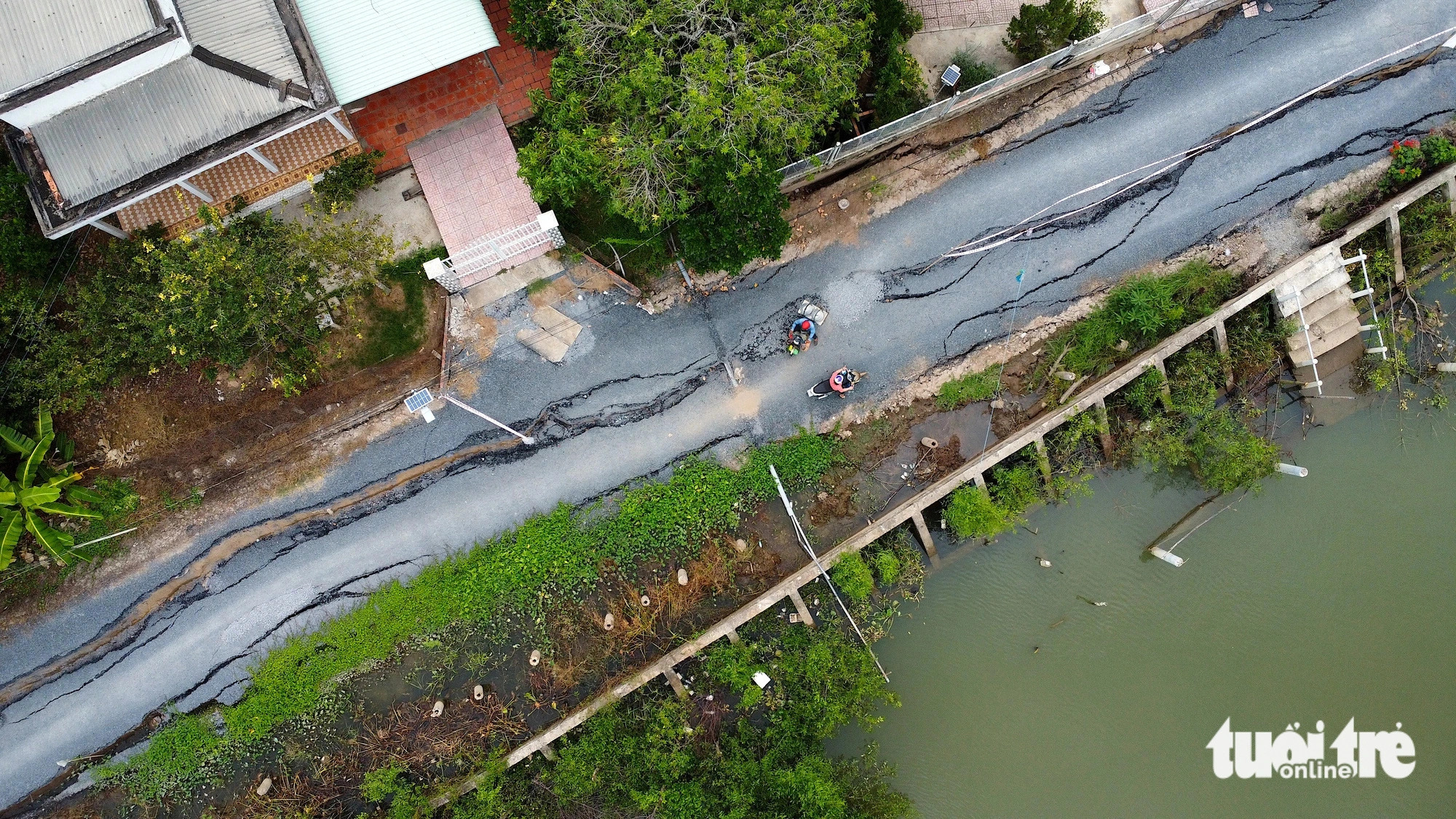 Local commuters try to pass through the road despite huge cracks. Photo: Mau Truong / Tuoi Tre