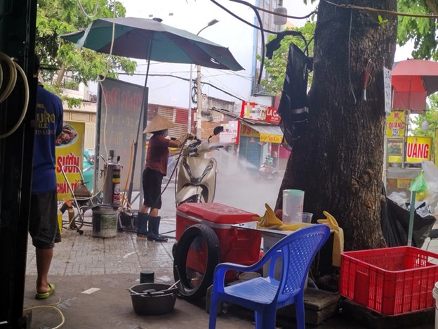 A vehicle washing shop on Pham Van Bach Street in Go Vap District, Ho Chi Minh City splashes water on the street, forcing many road users to dodge the water spray. Photo: Song Khue / Tuoi Tre