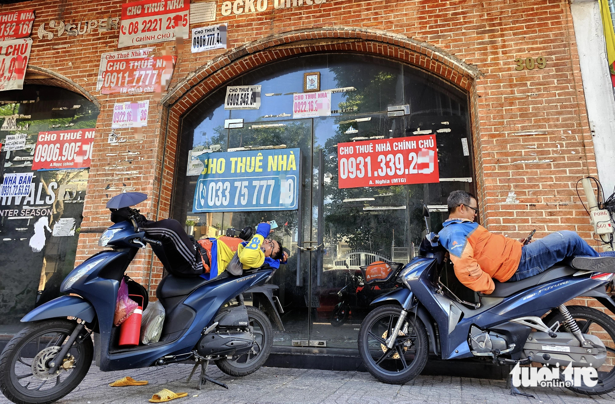 Motorbike taxi drivers rest under the porch of a vacant retail premises on Le Van Sy Street in District 3, Ho Chi Minh City. Photo: Ngoc Hien / Tuoi Tre
