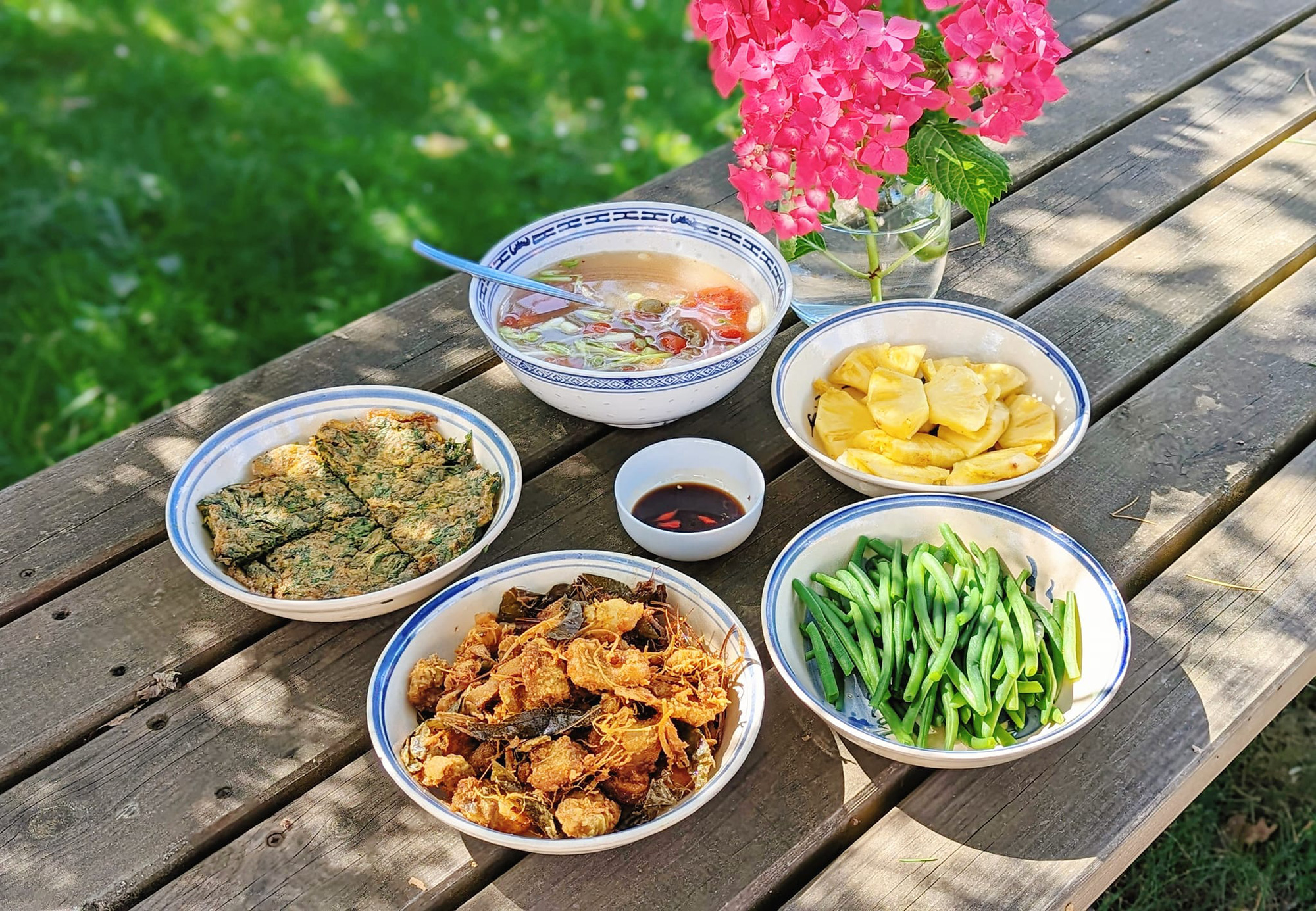 A meal containing fried eggs with mugwort, fried pork belly with galangal, fermented rice and clausena indica leaves, boiled home-grown green beans, and minced meat and dracontomelon fruit soup prepared by Do Thuy Linh in France. Photo: Supplied