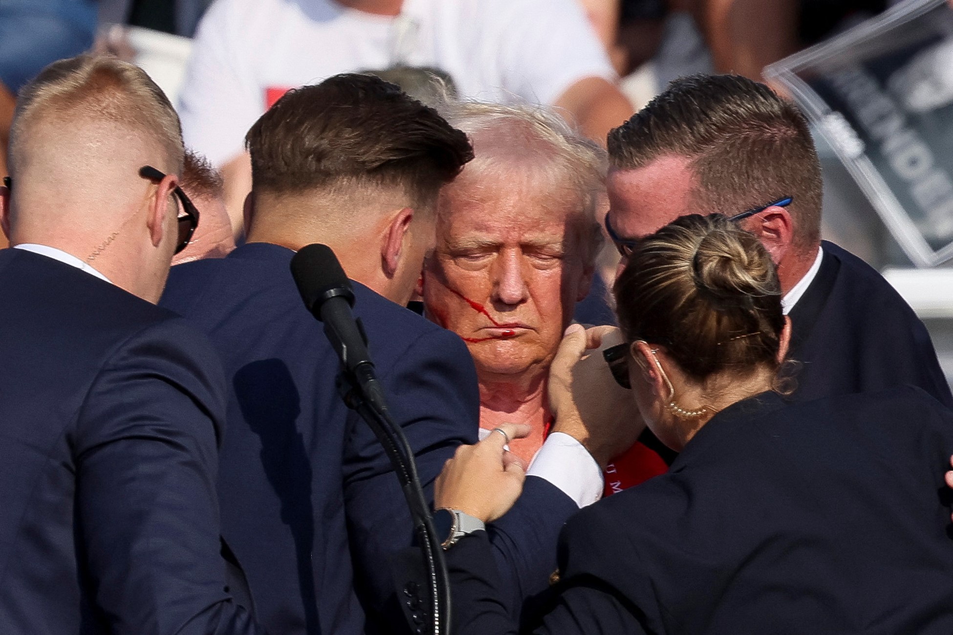 Republican presidential candidate and former U.S. President Donald Trump is assisted by security personnel after gunfire rang out during a campaign rally at the Butler Farm Show in Butler, Pennsylvania, U.S., July 13, 2024. Photo: Reuters