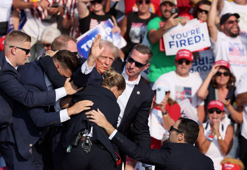 [11/16]Republican presidential candidate and former U.S. President Donald Trump gestures with a bloodied face while he is assisted by U.S. Secret Service personnel after he was shot in the right ear during a campaign rally at the Butler Farm Show in Butler, Pennsylvania, U.S., July 13, 2024. Photo: Reuters