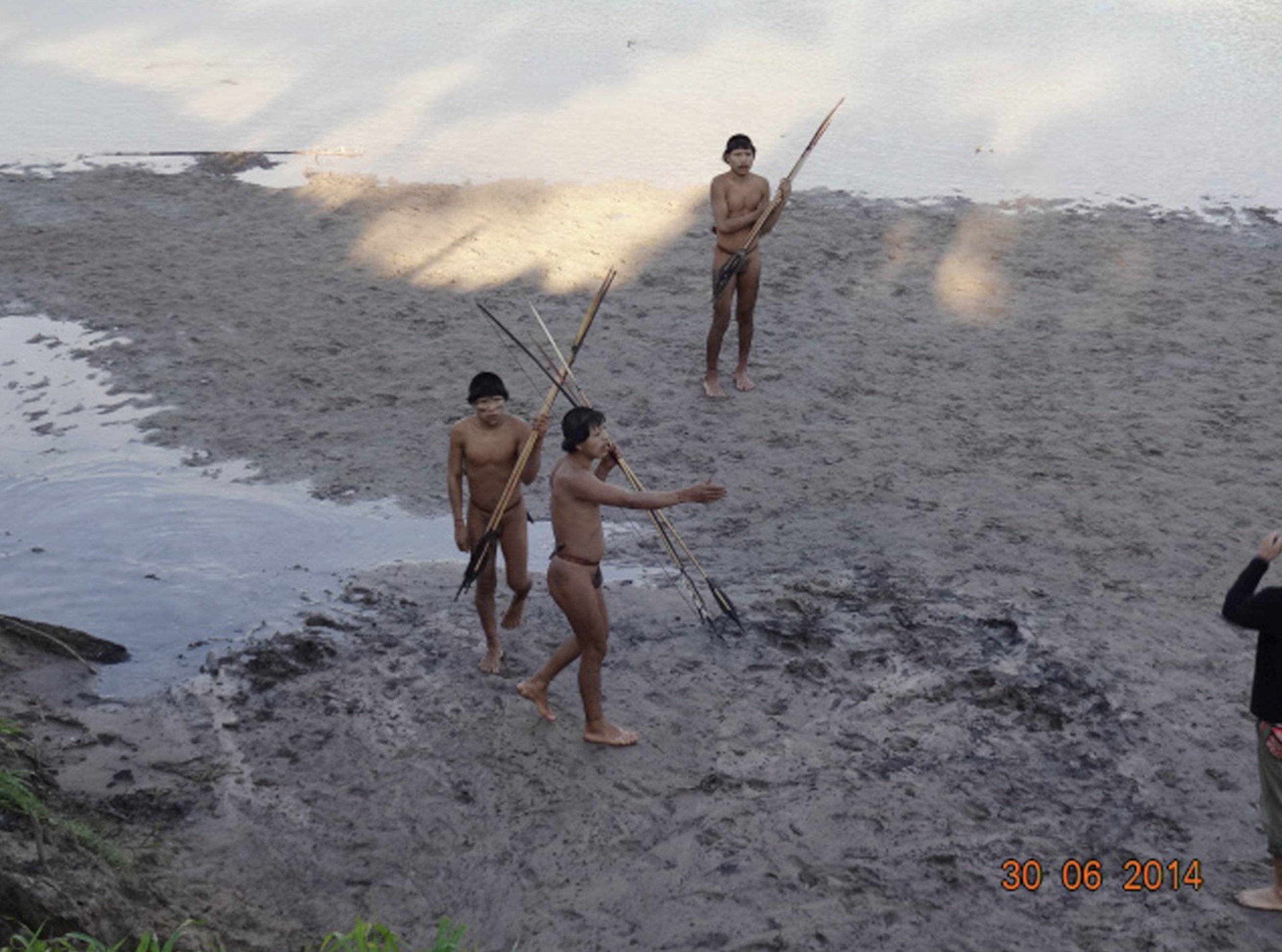 Three members of a previously uncontacted tribe make voluntary contact with a team of researchers (R, edge of photo) from Brazil's National Indian Foundation (FUNAI) on the bank of the Envira river in Aldeia Simpatia, Acre state, June 30, 2014. Photo: Reuters