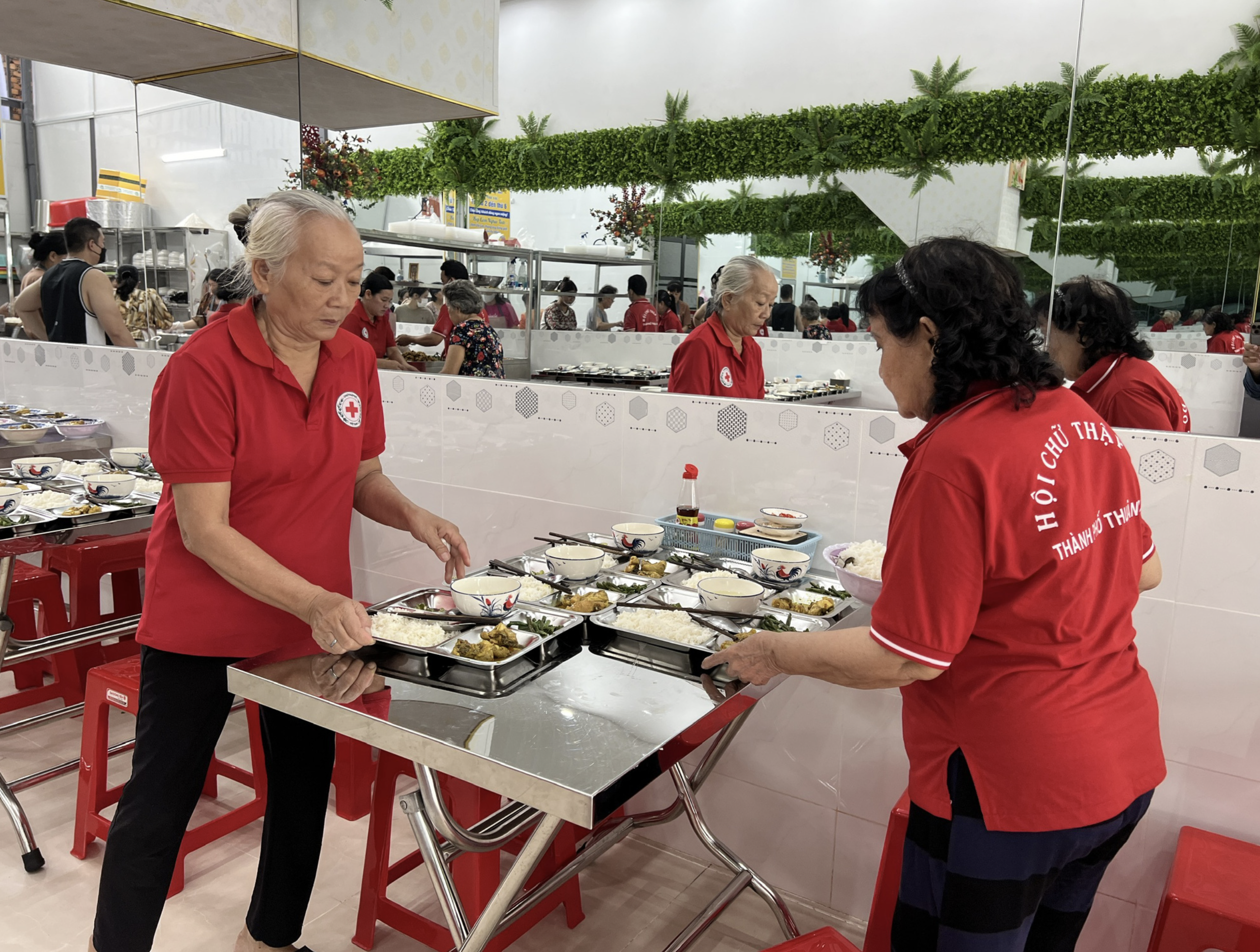 Some members of the Red Cross unit in Lai Thieu Ward, Binh Duong Province help serve poor people at a kitchen which offers free meals. Photo: Xuan Doan / Tuoi Tre