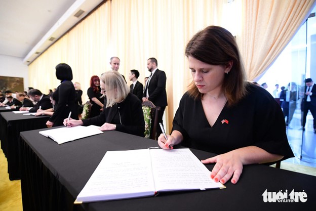 A foreign guest in Ho Chi Minh City writes in the condolence book for Party General Secretary Nguyen Phu Trong. Photo: Quang Dinh / Tuoi Tre