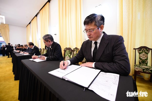 The consul general of China in Ho Chi Minh City writes in the condolence book for Party General Secretary Nguyen Phu Trong. Photo: Quang Dinh / Tuoi Tre