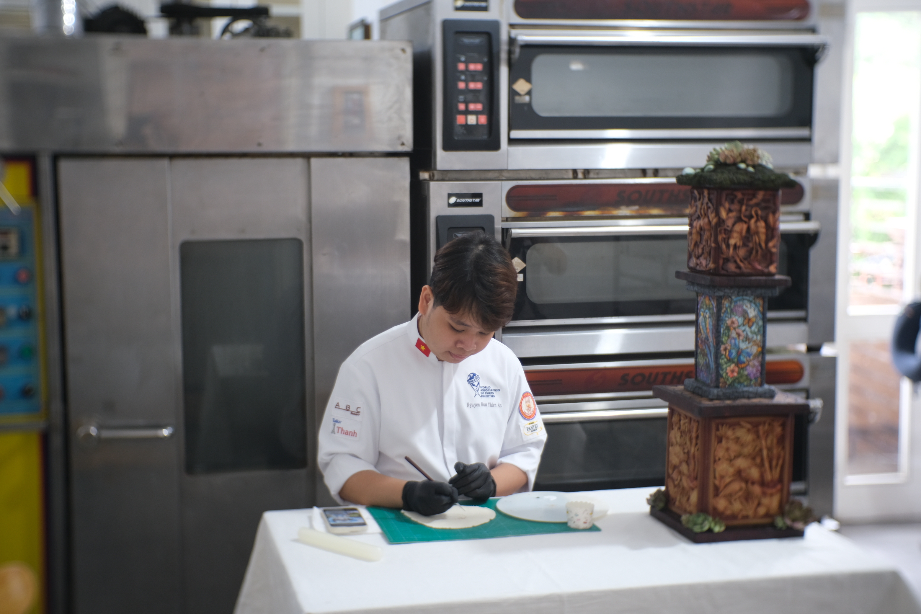 Nguyen Huu Thien An is painting on a piece of flattened fondant. Photo: Ngoc Phuong / Tuoi Tre News