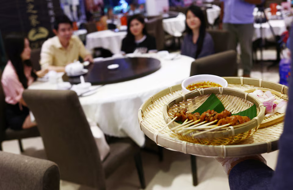 Restaurant owner Francis Ng serves satay sprinkled with house crickets to invited food tasters at the House of Seafood restaurant in Singapore July 16, 2024. Photo: Reuters