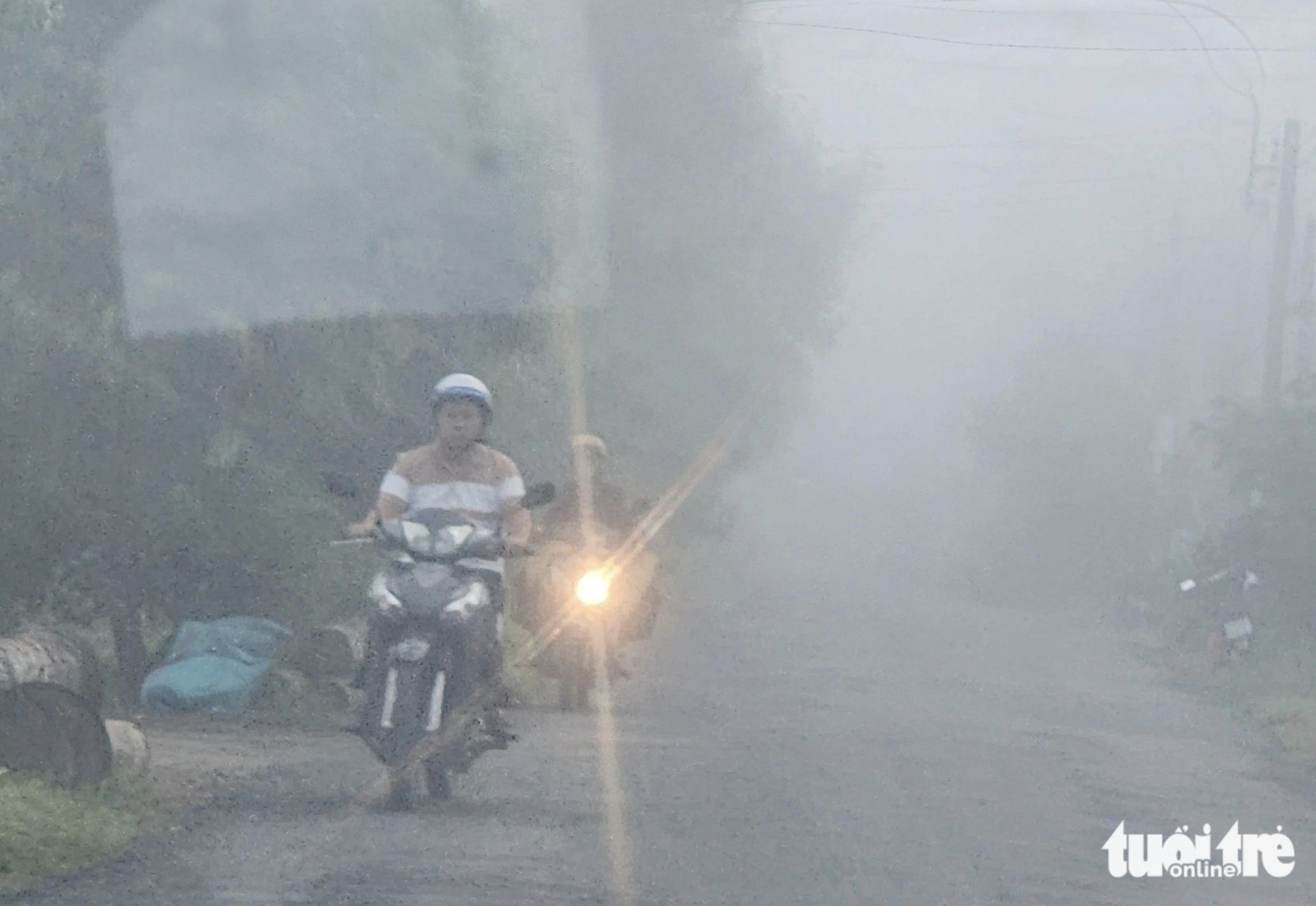 A motorcycle has its headlight turned on due to poor visibility caused by thick fog. Photo: Hoai Thuong / Tuoi Tre