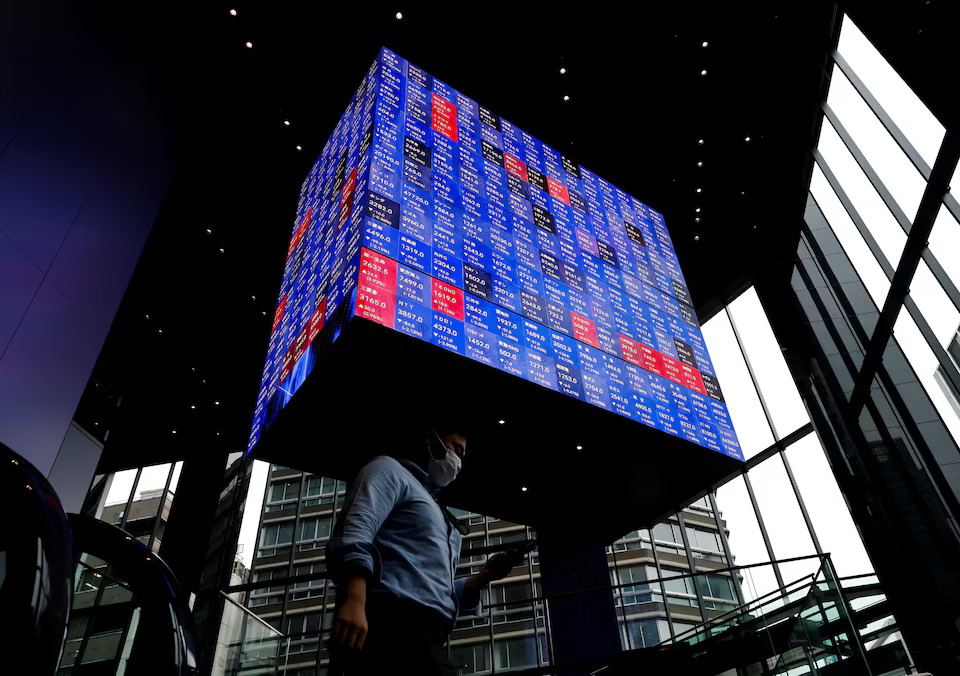 A man walks under an electronic screen showing Japan's Nikkei share price index inside a conference hall in Tokyo, Japan June 14, 2022. Photo: Reuters