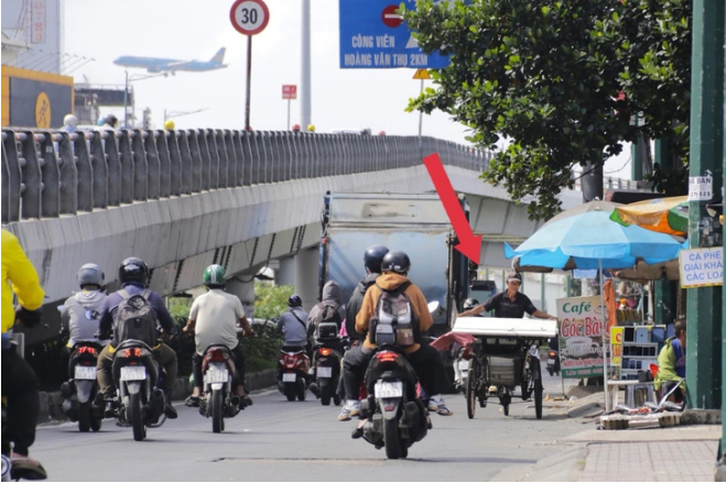 A three-wheeler also travels in the opposite direction with motorbikes while carrying bulky things. Photo:  Tien Quoc / Tuoi Tre