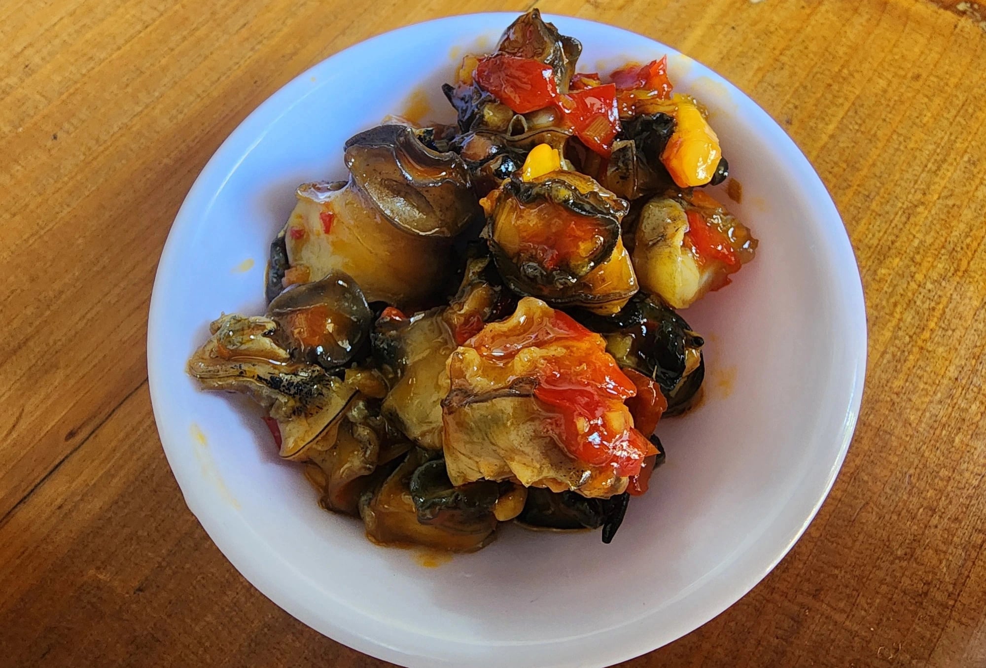 A bowl of sautéed snails seasoned with aromatic satay served with a bowl of ‘bún riêu cua biển’ at Bún Riêu Ốc 5 Không shop in Phan Rang City, Ninh Thuan Province, south-central Vietnam. Photo: Nha Xuan / Tuoi Tre