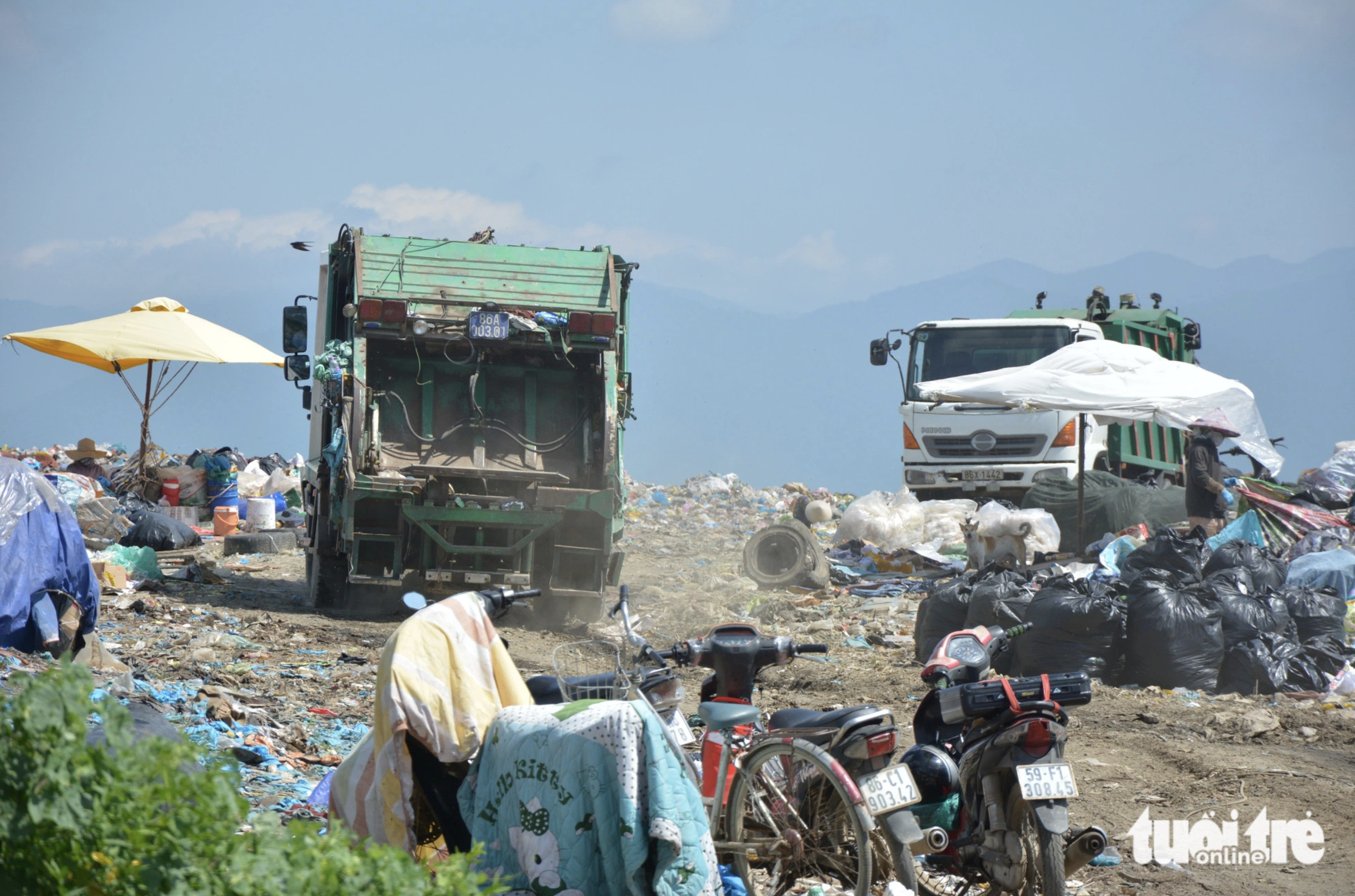 Locals scavenge for recyclable or usable items around garbage trucks at Binh Tu Landfill. Photo: Duc Trong / Tuoi Tre