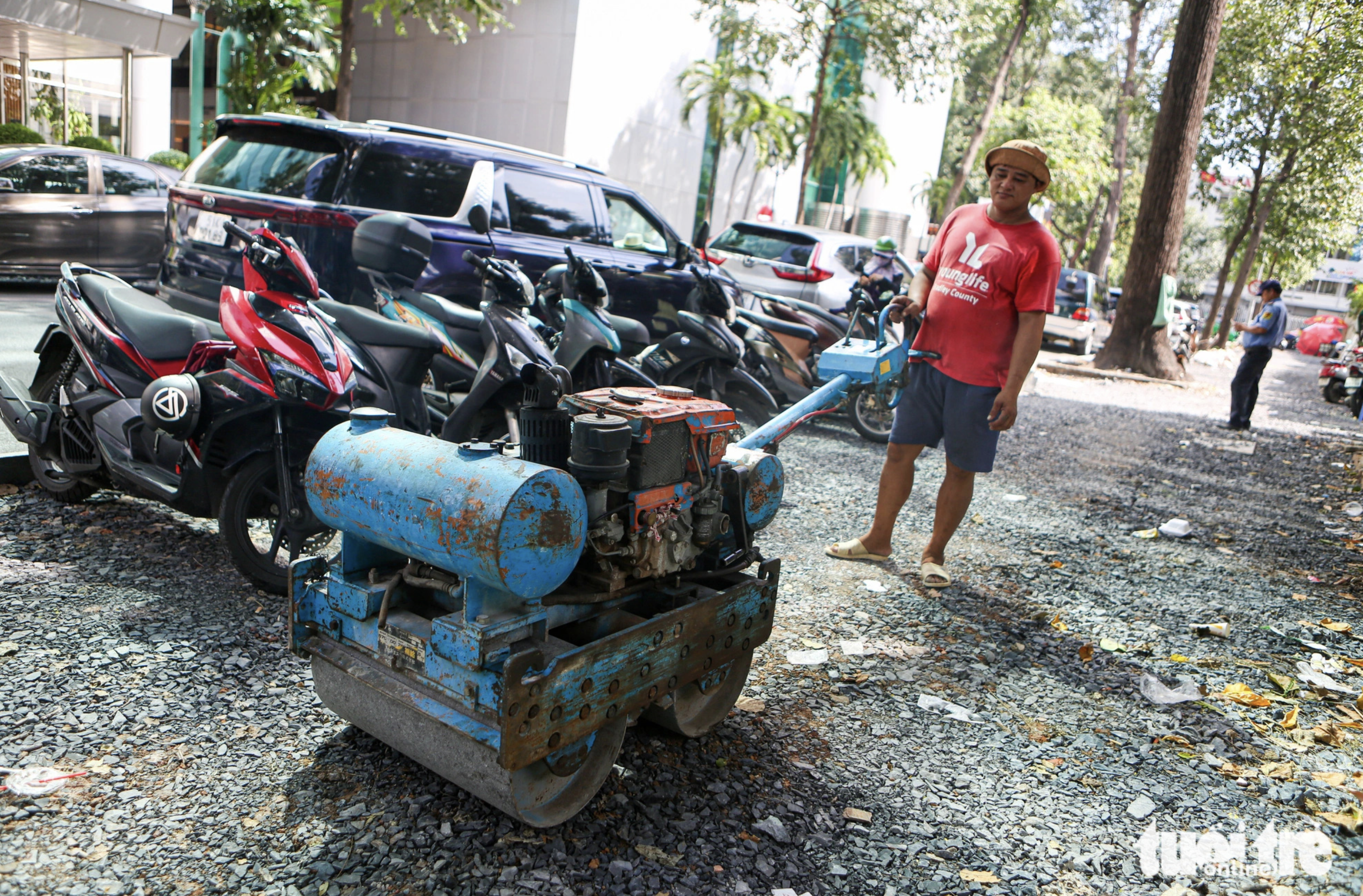 A worker is pictured leveling out the surface of a damaged pavement before repaving it downtown Ho Chi Minh City.