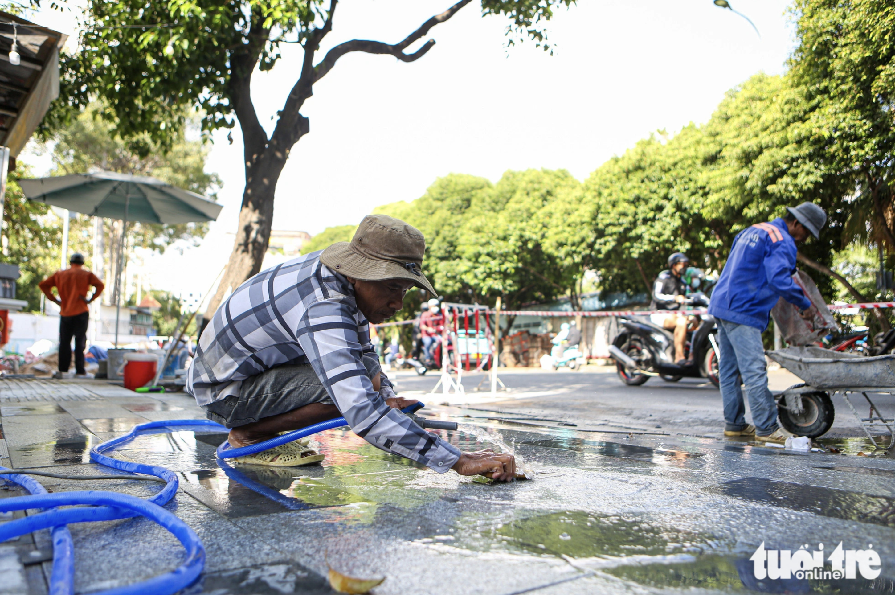 A road worker cleans a new layer of tiles on a pavement in downtown Ho Chi Minh City.