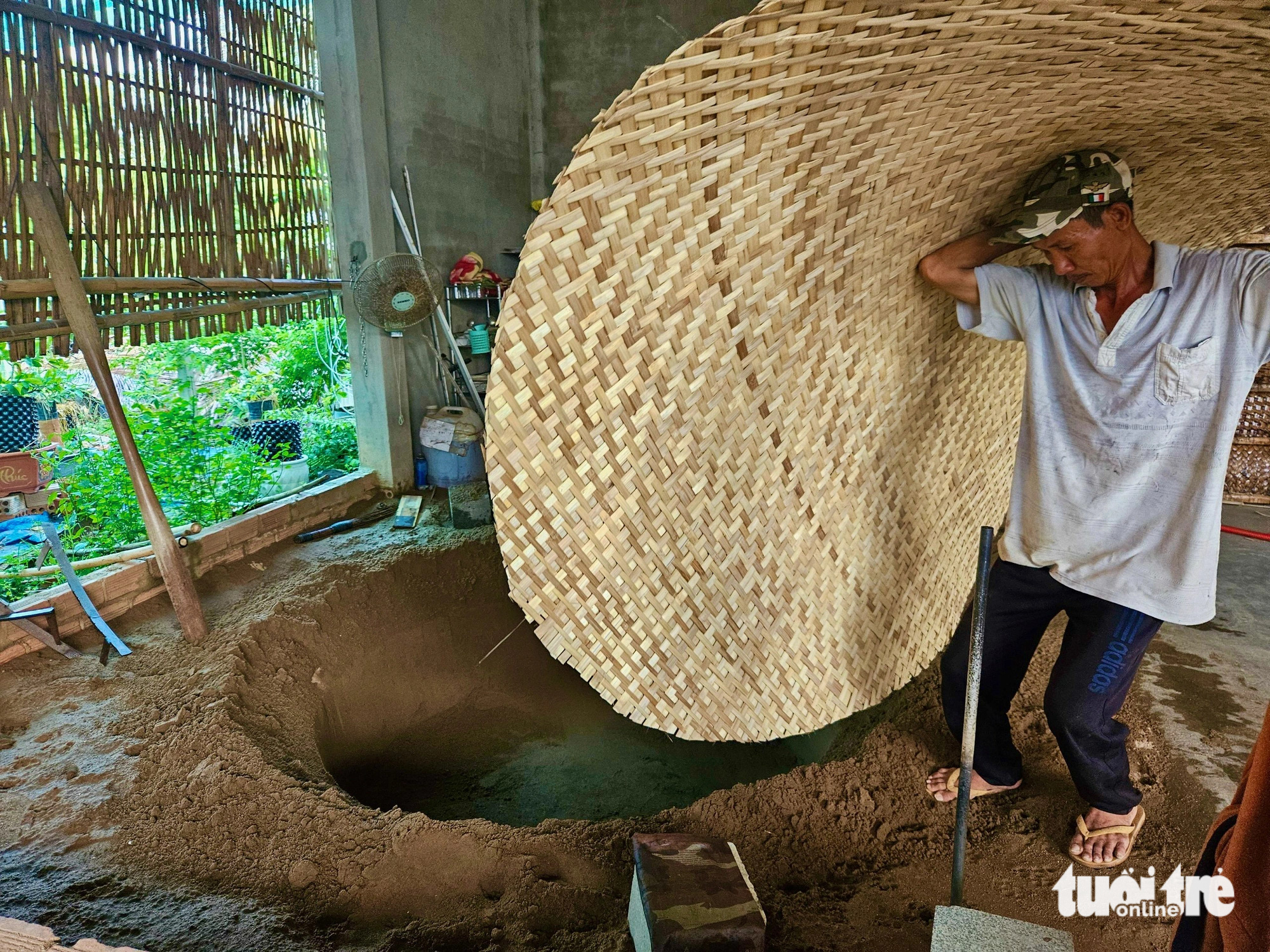 Truong Van Trung places a completed basket mat into a dug pit to shape a basket boat bottom at Phu My basket boat craft village in Tuy An District, Phu Yen Province, south-central Vietnam. Photo: Minh Chien / Tuoi Tre