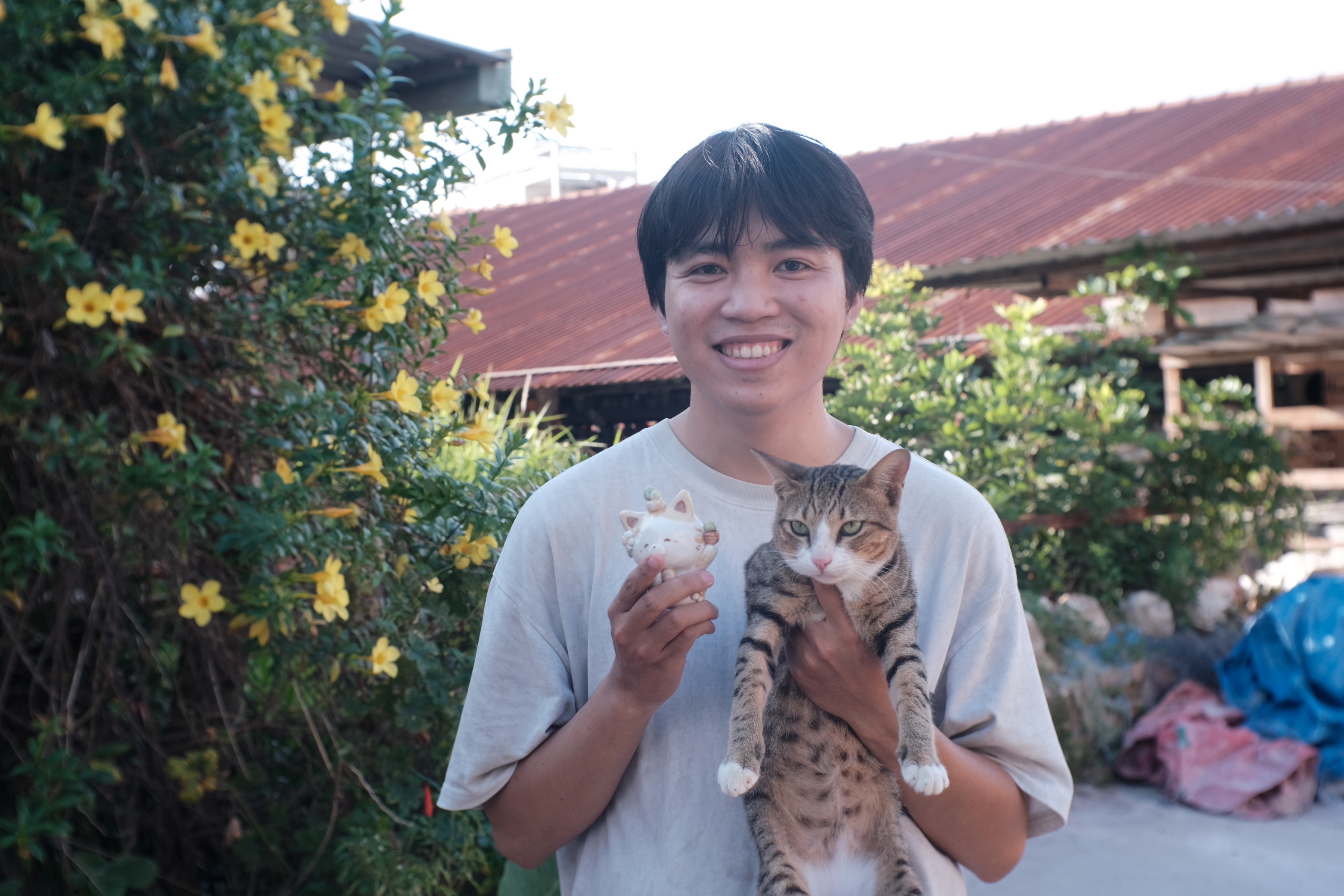 Hoang Anh Tu poses with a cat and a cat figurine. Photo: Ngoc Phuong / Tuoi Tre News