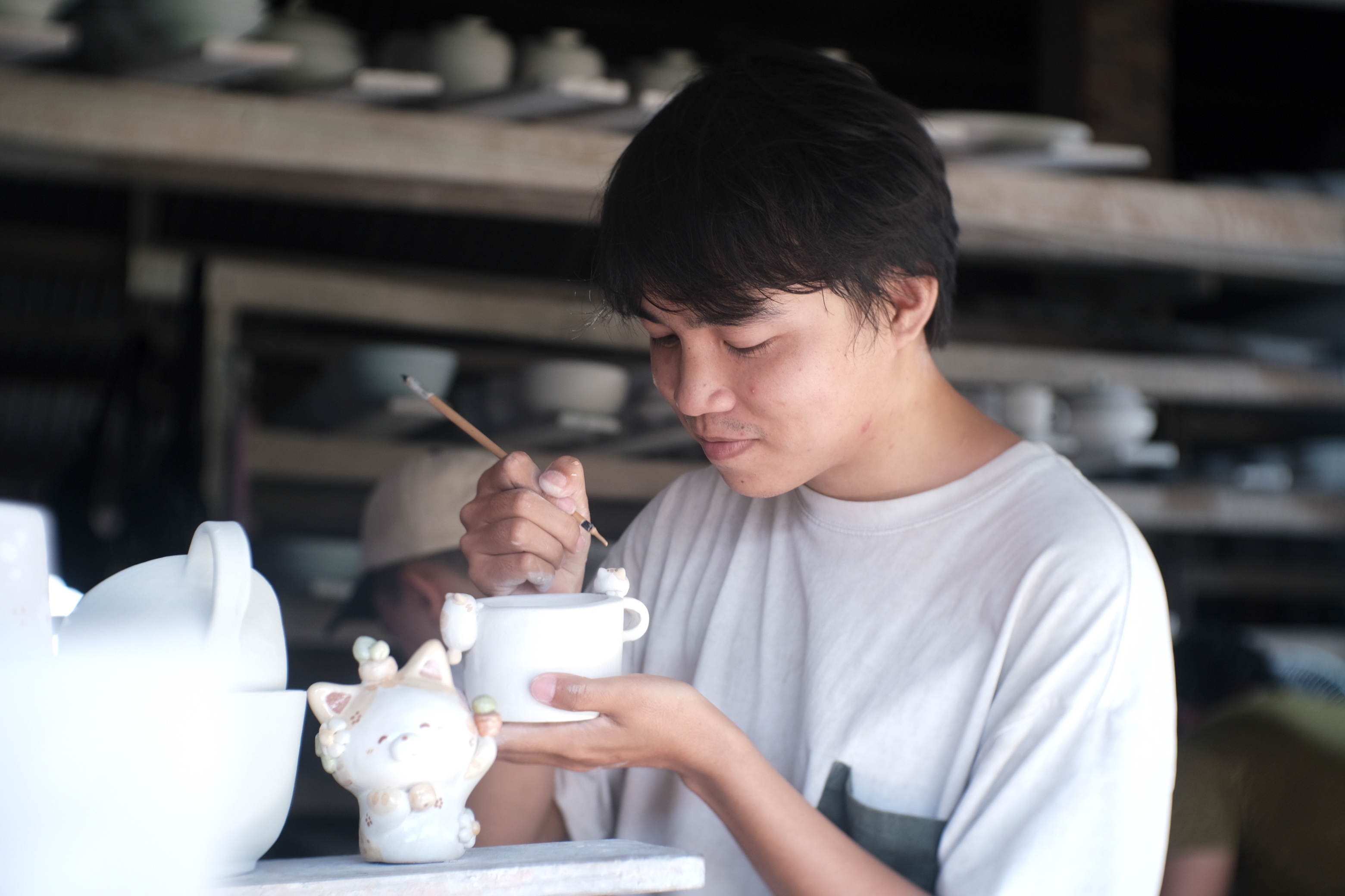 Tu paints on a ceramic cat-themed mug. Photo: Ngoc Phuong / Tuoi Tre News