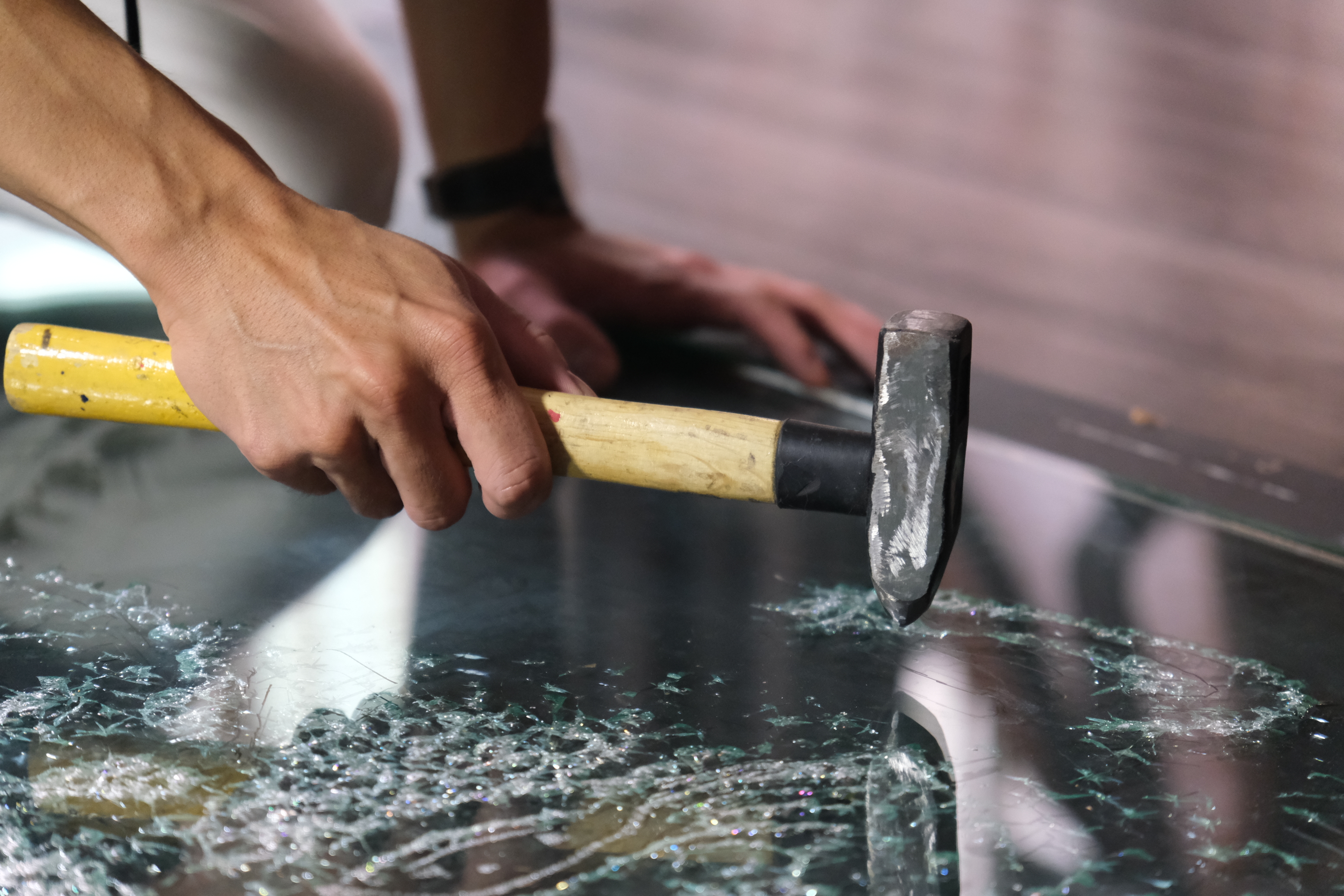 Nguyen Thang uses a hammer with a pointed end to tap on the surface of laminated glass to create glass art. Photo: Ngoc Phuong / Tuoi Tre News