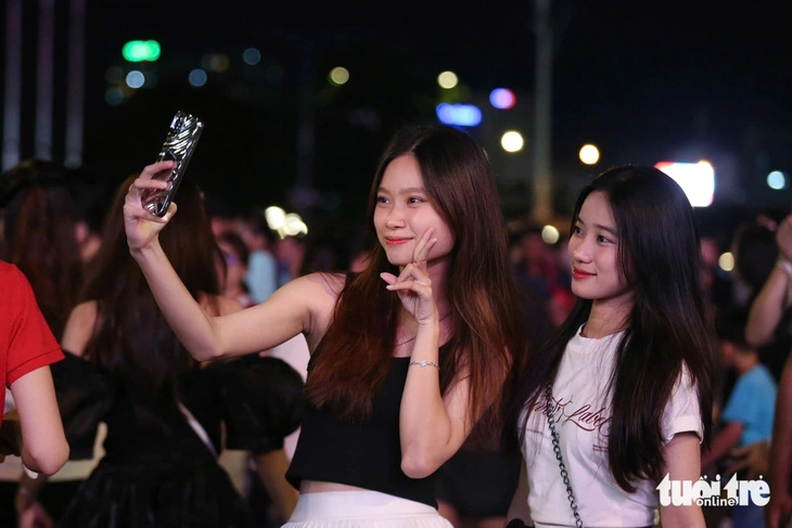 Two young girls take a wefie among a crowd gathering in District 1, Ho Chi Minh City on September 2, 2024 to enjoy a fireworks display marking Vietnam’s 79th National Day. Photo: Phuong Quyen / Tuoi Tre