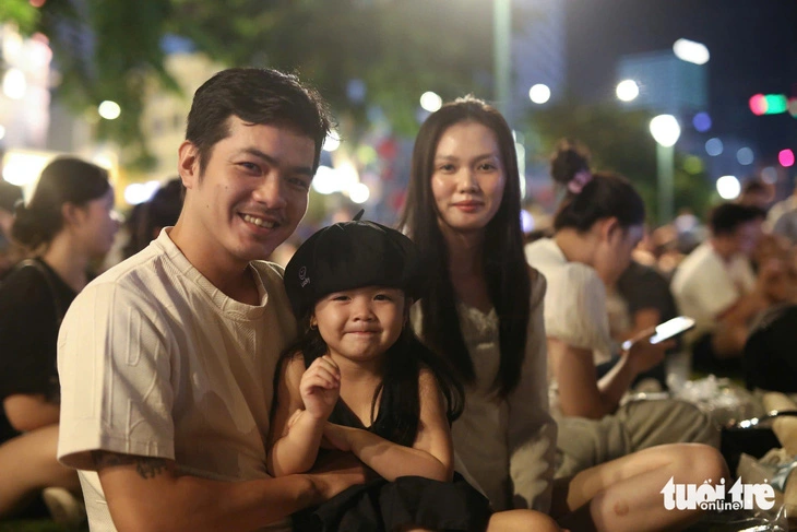 A couple and their child are seen among a crowd sitting at the Bach Dang Wharf Park in District 1, Ho Chi Minh City on September 2, 2024 to wait for viewing a fireworks show marking Vietnam’s 79th National Day. Photo: Phuong Quyen / Tuoi Tre