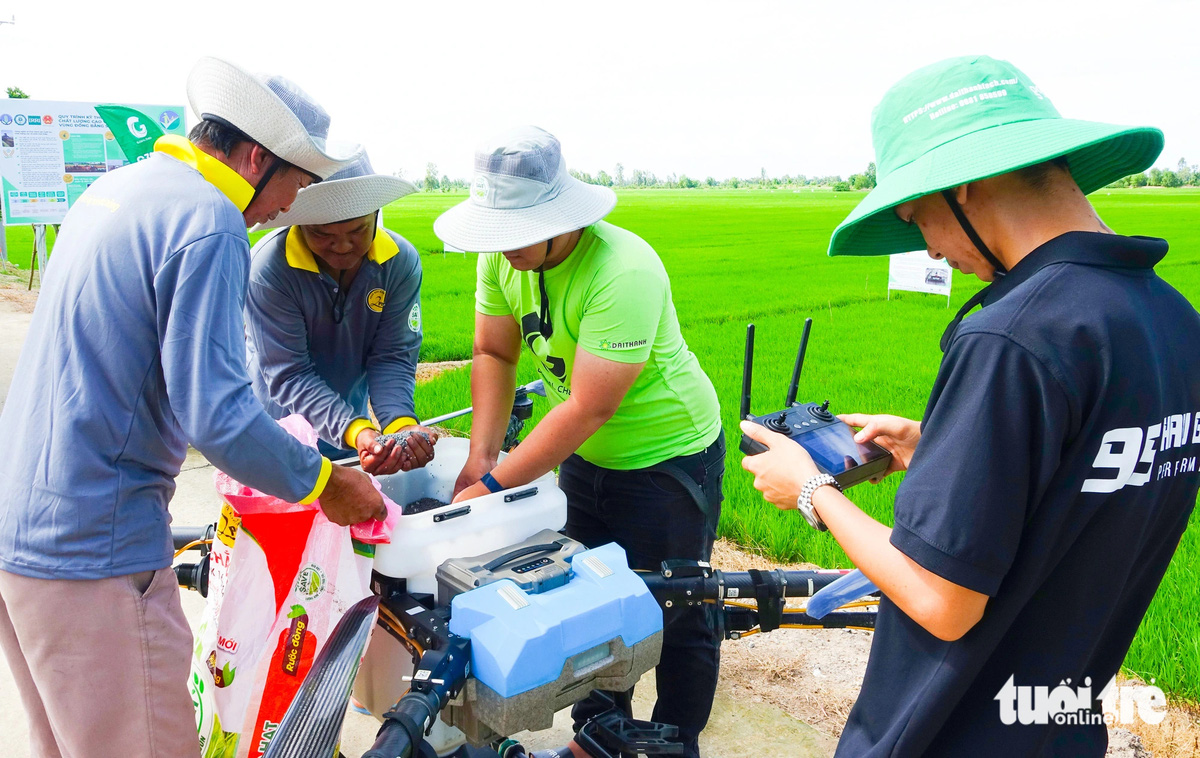 Farmers prepare a fertilizer container before a drone flight over rice fields in the Mekong Delta region, southern Vietnam. Photo: Chi Cong / Tuoi Tre