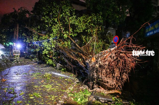 Police officers and workers clean a street in Hanoi after typhoon Yagi hits the city. Photo: Hong Quang / Tuoi Tre