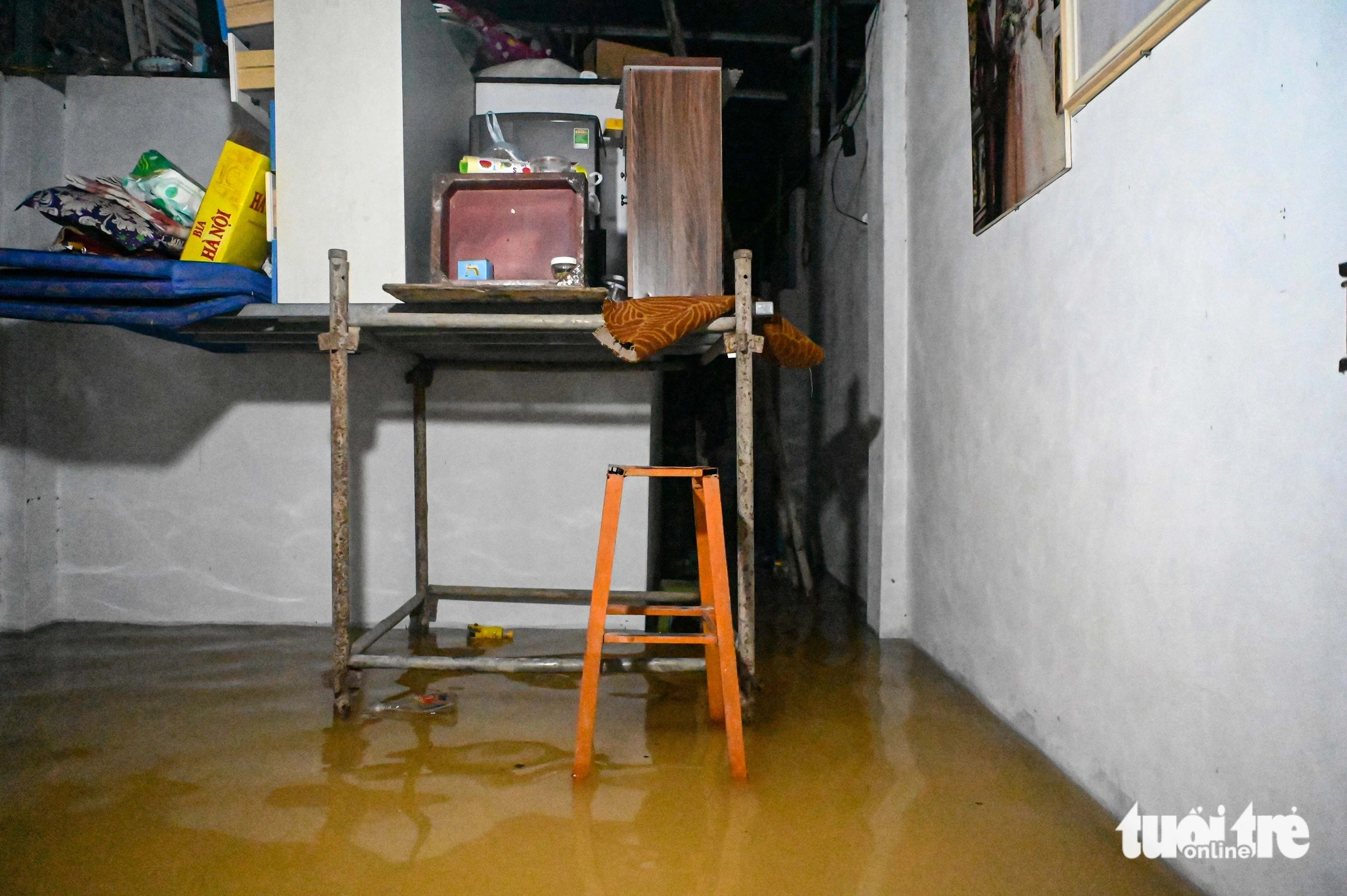 A man stands in front of his flooded house in Hanoi after putting assets in higher places. Photo: Hong Quang / Tuoi Tre