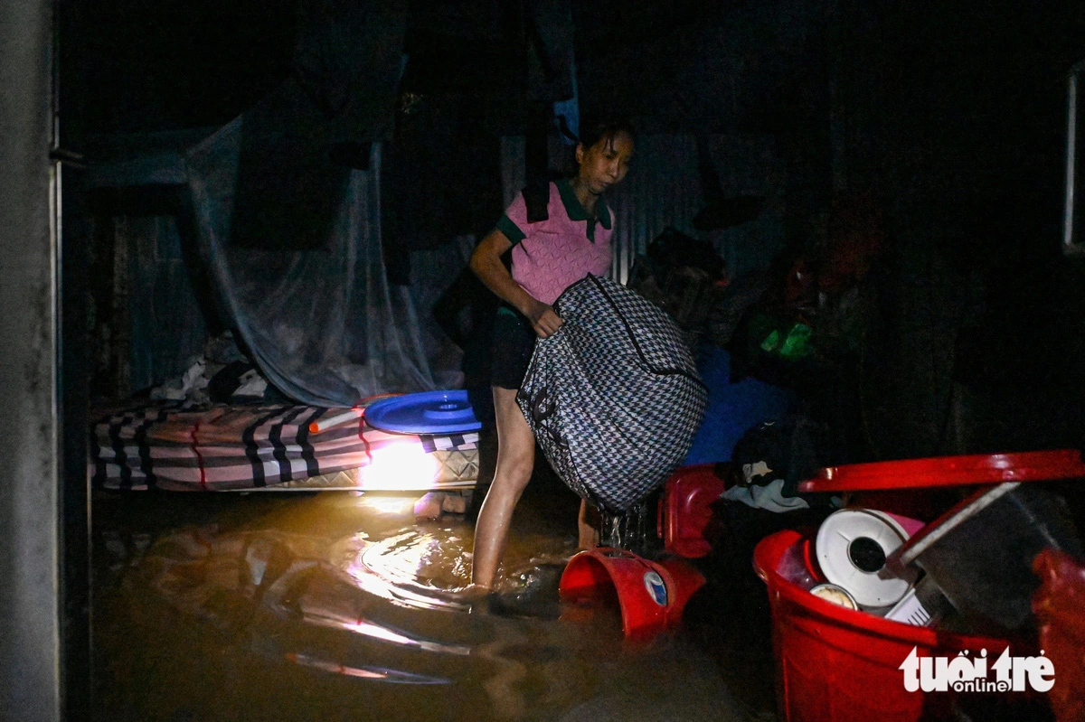 Bich Phuong, a resident of Tay Ho District, Hanoi, hurriedly puts her belongings to higher places as her house floods. Photo: Hong Quang / Tuoi Tre