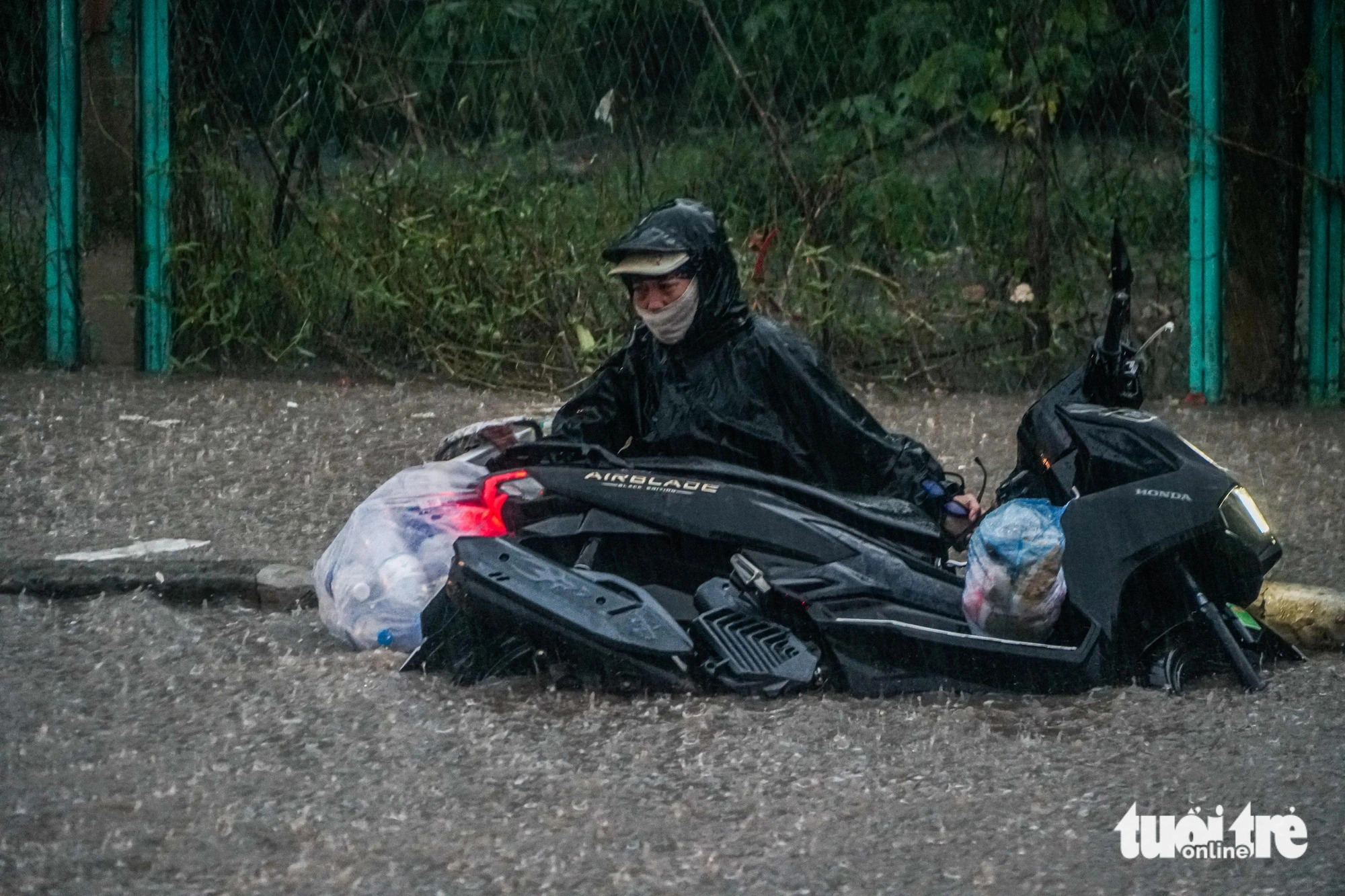 A motorcyclist fell off her bike while attempting to pass through a waterlogged area in Hanoi, September 9, 2024. Photo: Pham Tuan / Tuoi Tre