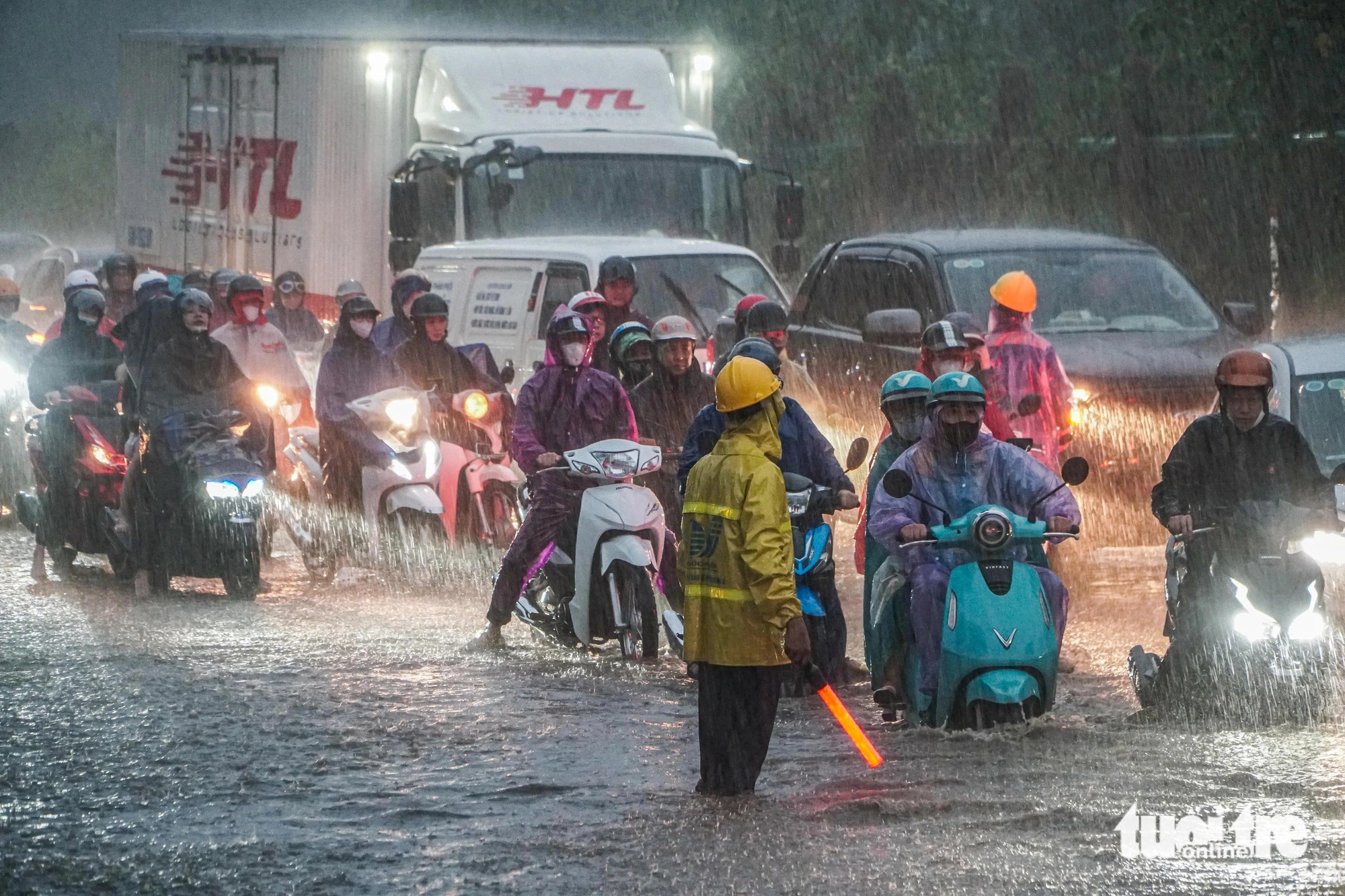 A Hanoi Sewerage And Drainage Company employee instructs road users to avoid heavily-flooded spots in Hanoi, September 9, 2024. Photo: Pham Tuan / Tuoi Tre