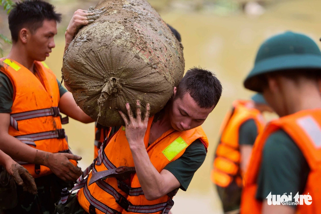 Military officers remove bags of rice from a collapsed house as they hunt for missing victims. Photo: Nguyen Khanh / Tuoi Tre