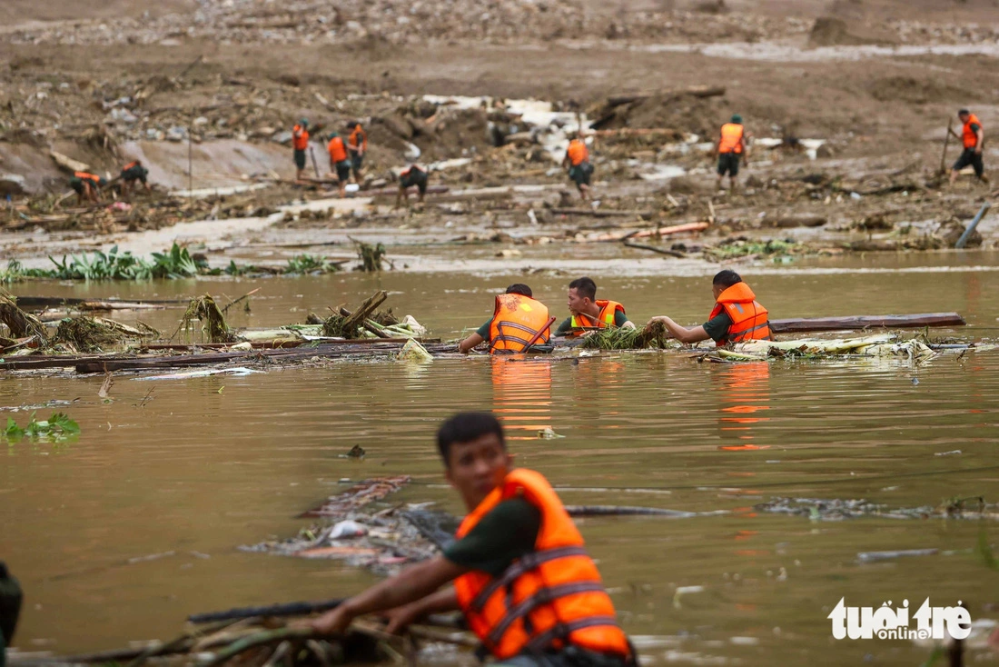 Military officers wade through water and mud as they search for missing victims. Photo: Nguyen Khanh / Tuoi Tre