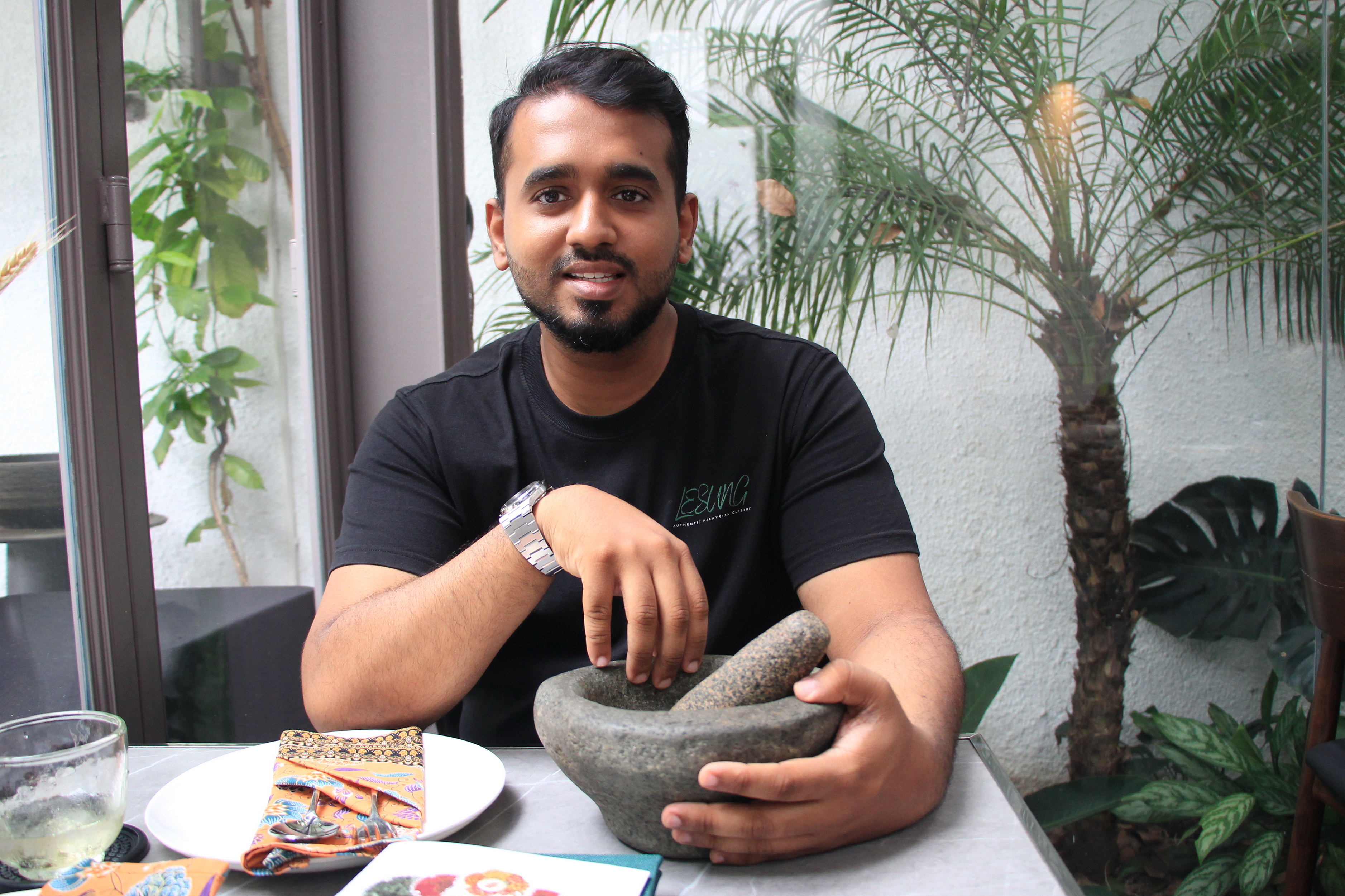 Malaysian Chef Eden Daus poses for a photo with a 150-year-old traditional stone mortar and pestle passed down from his grandmother at his Malaysian authentic restaurant Lesung in District 3, Ho Chi Minh City. Photo: Dong Nguyen / Tuoi Tre News