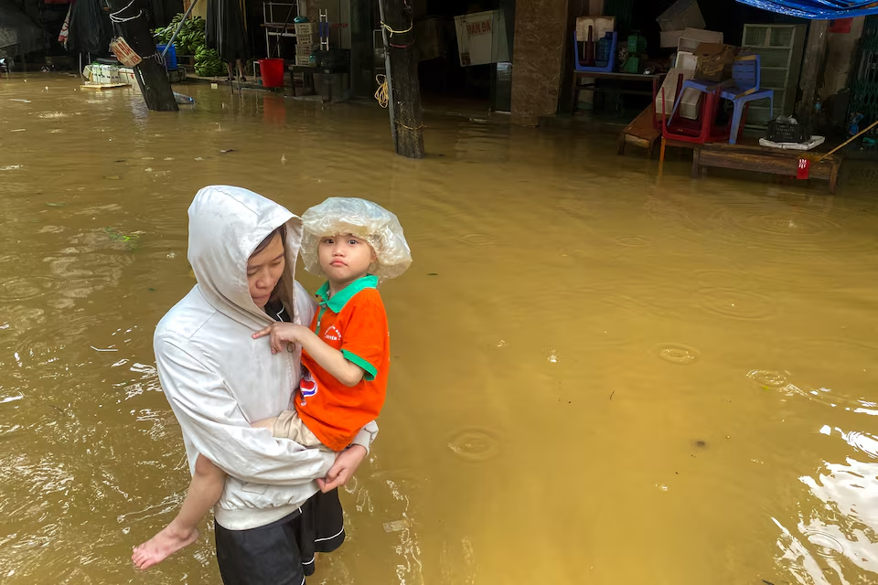 A woman holds a boy as she wades through a flooded street following the impact of Typhoon Yagi in Thai Nguyen City, Vietnam, September 11, 2024. Photo: Reuters