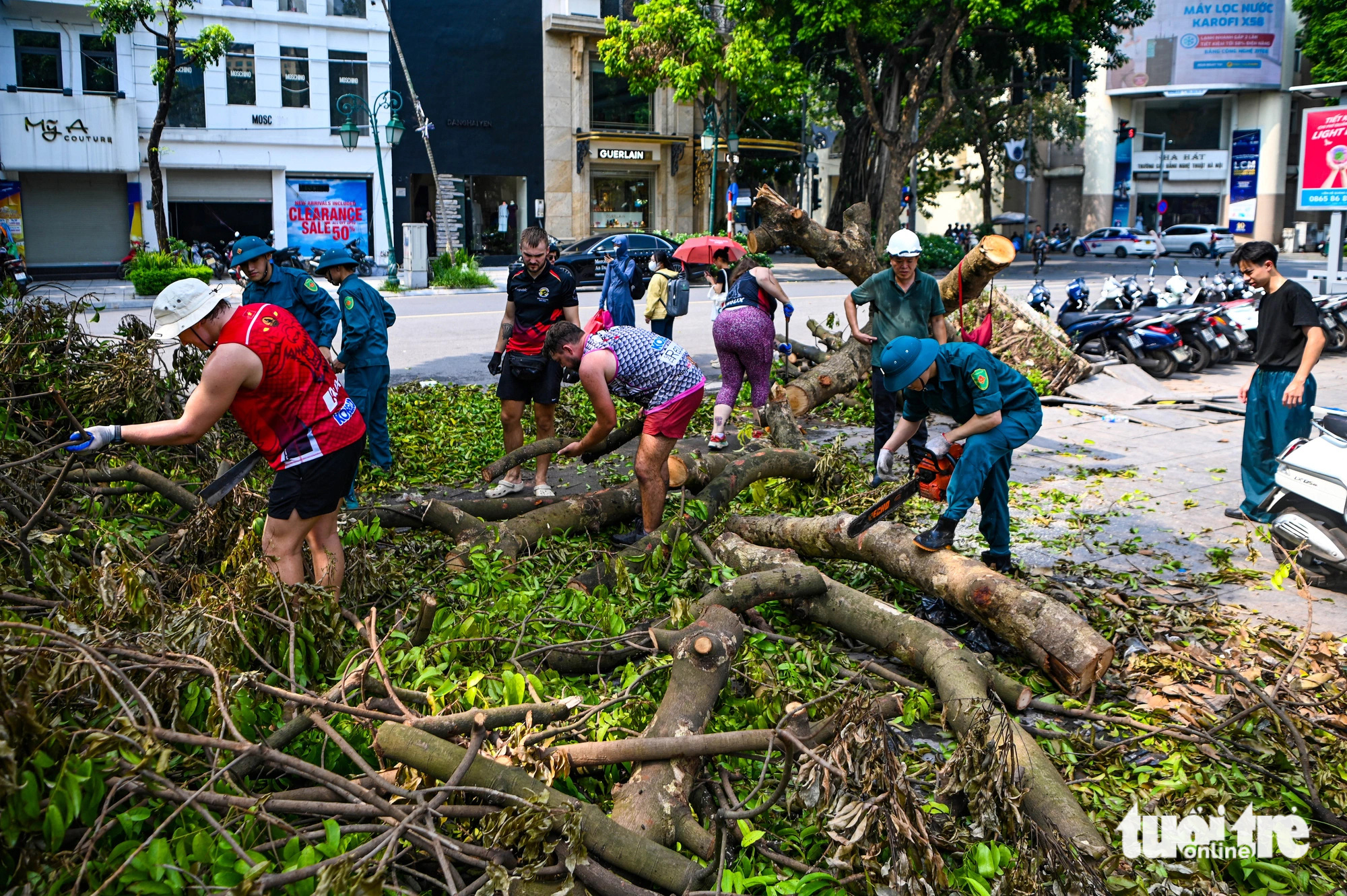 Foreigners help clear fallen tree branches on the street in Hoan Kiem District, Hanoi, September 14, 2024. Photo: Hong Quang / Tuoi Tre