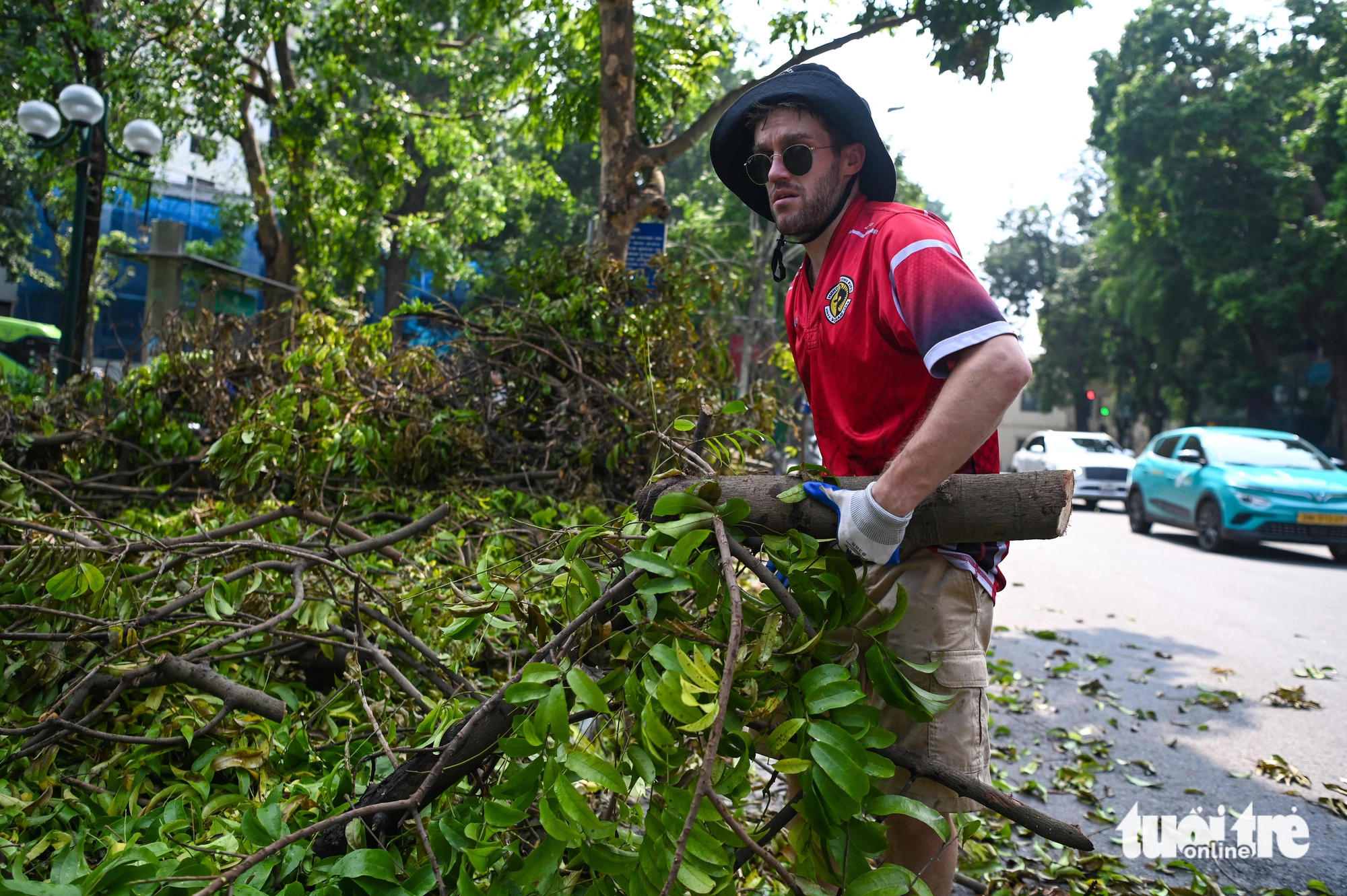 A foreigner helps clear fallen tree branches on the street in Hoan Kiem District, Hanoi, September 14, 2024. Photo: Hong Quang / Tuoi Tre