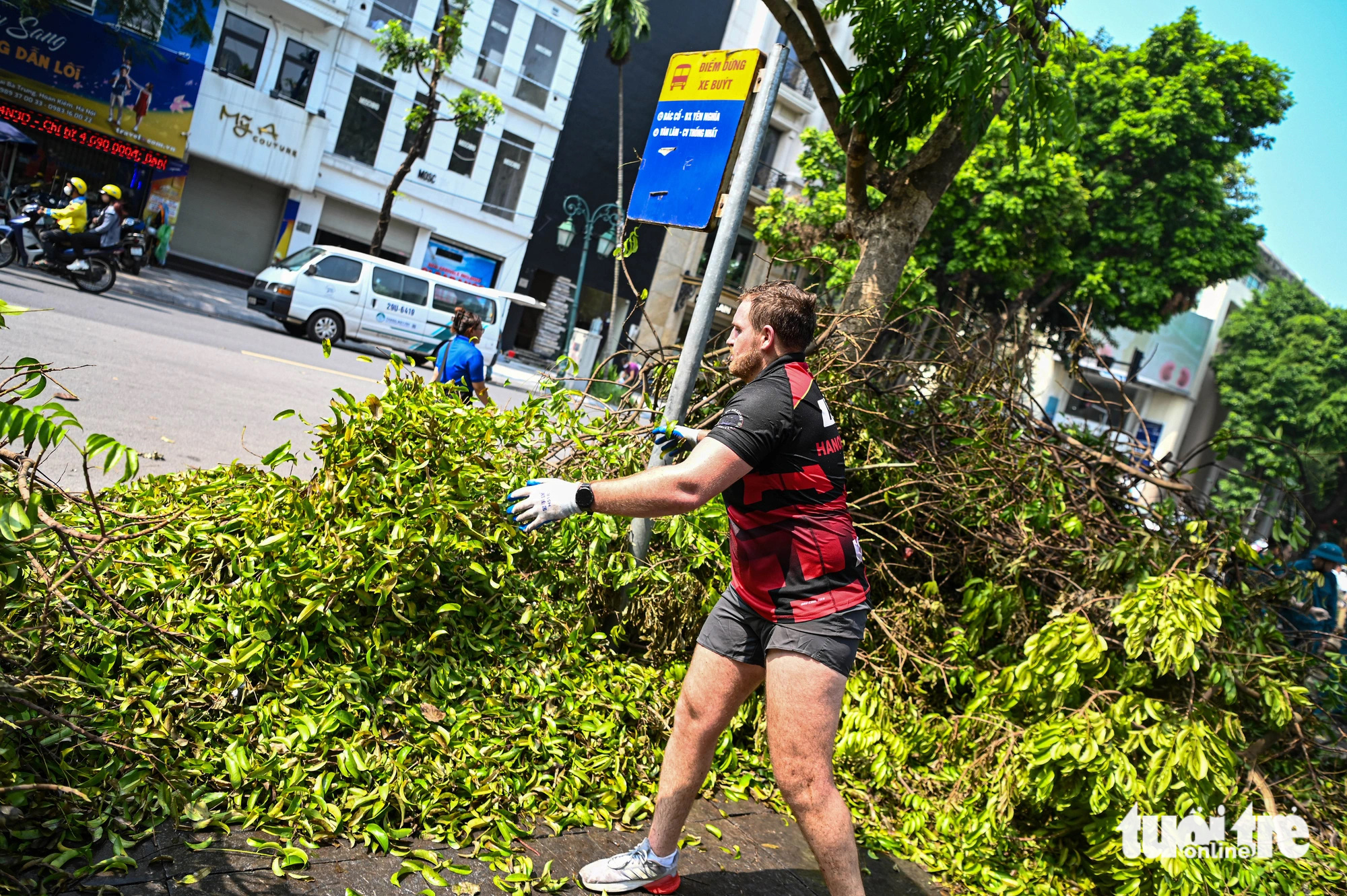 A foreigner helps clear fallen tree branches on the street in Hoan Kiem District, Hanoi, September 14, 2024. Photo: Hong Quang / Tuoi Tre