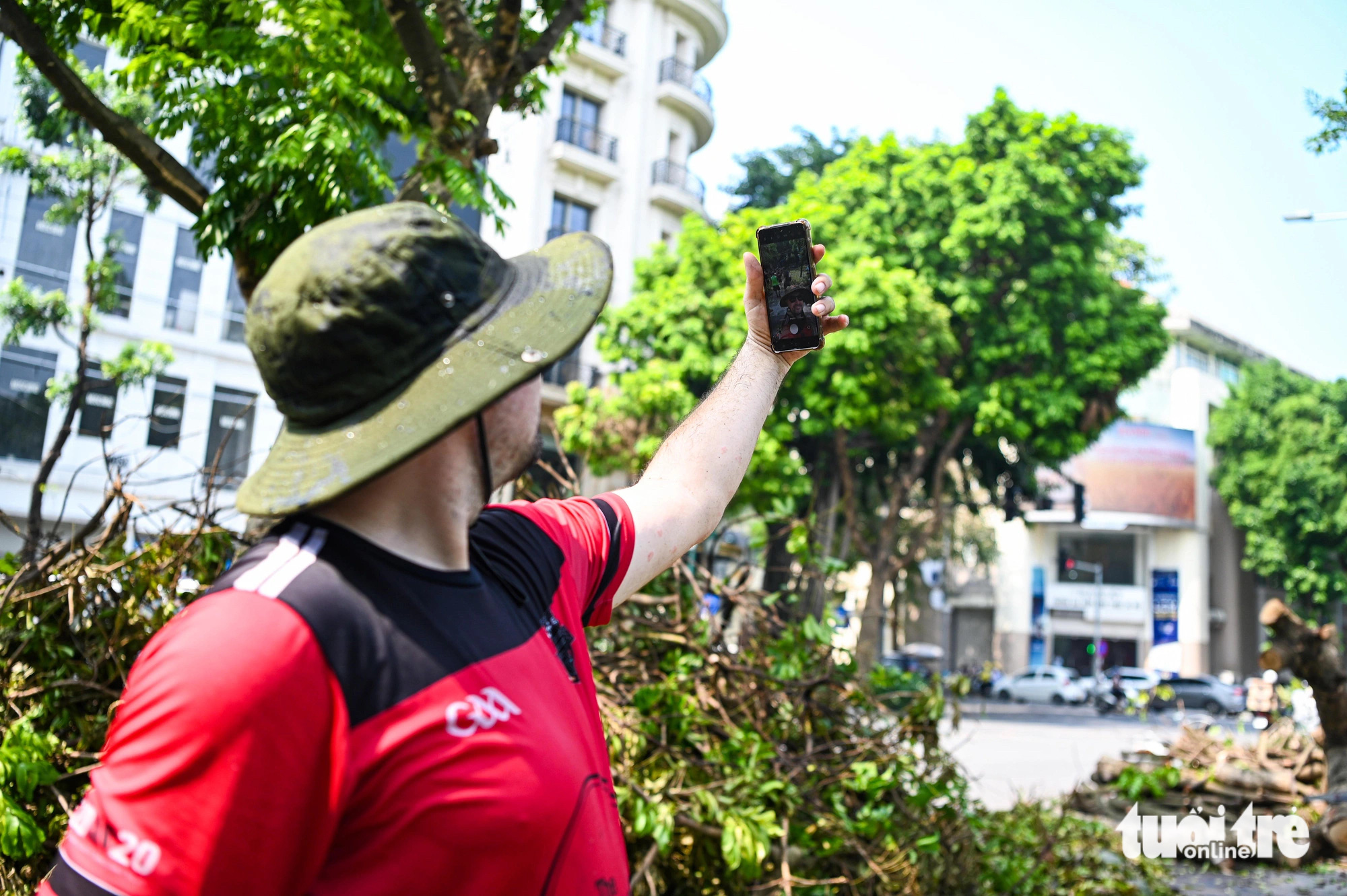 A foreigner takes a selfie while clearing fallen tree branches on the street in Hoan Kiem District, Hanoi, September 14, 2024. Photo: Hong Quang / Tuoi Tre