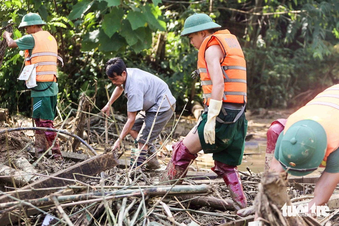 Thoi and military officers turn over each wood and bamboo bars to find his son. Photo: Nguyen Khanh / Tuoi Tre