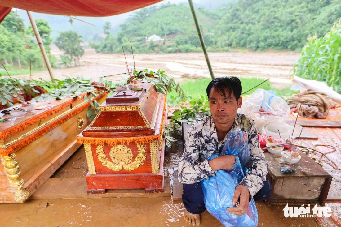 Thoi sits next to the coffins of his mother, wife, and two children in Lao Cai Province. Photo: Nguyen Khanh / Tuoi Tre