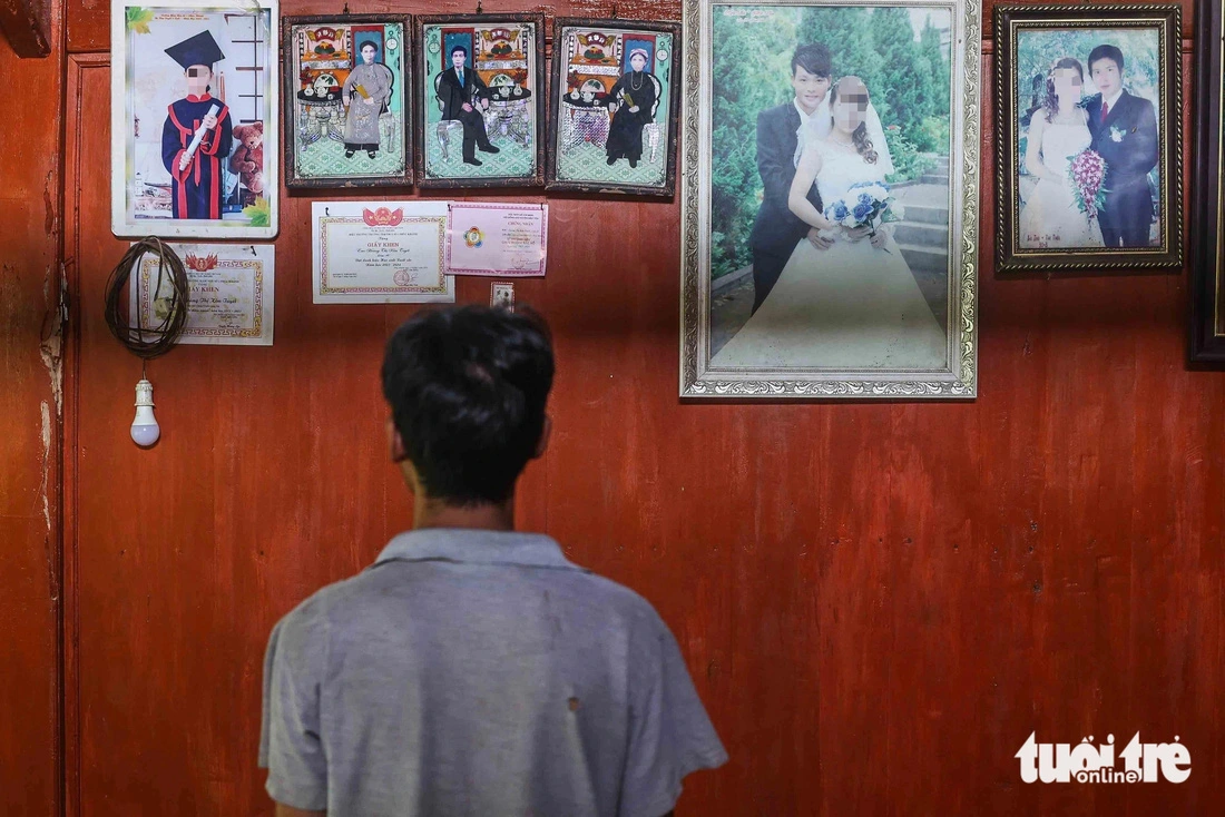 Thoi looks at photos of his family hanged in his house in Lao Cai Province. He lost his family and assets to the flood. Photo: Nguyen Khanh / Tuoi Tre