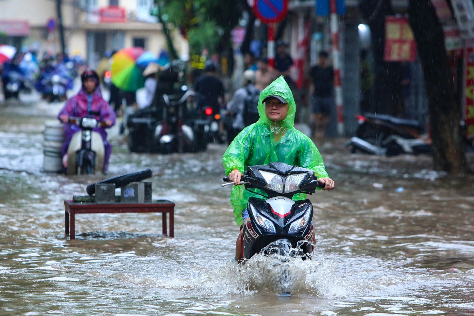 Motorcyclists struggle to wade through a waterlogged road section in Hanoi, September 16, 2024. Photo: Hong Quang / Tuoi Tre